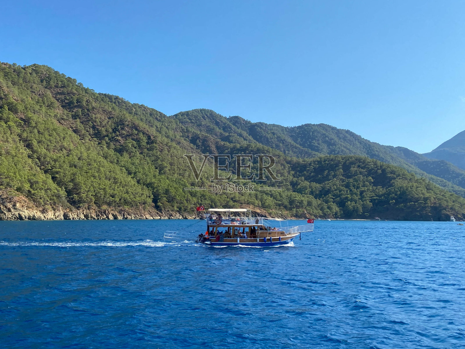 游艇在海中央，以山脉和蓝色的云层为背景照片摄影图片