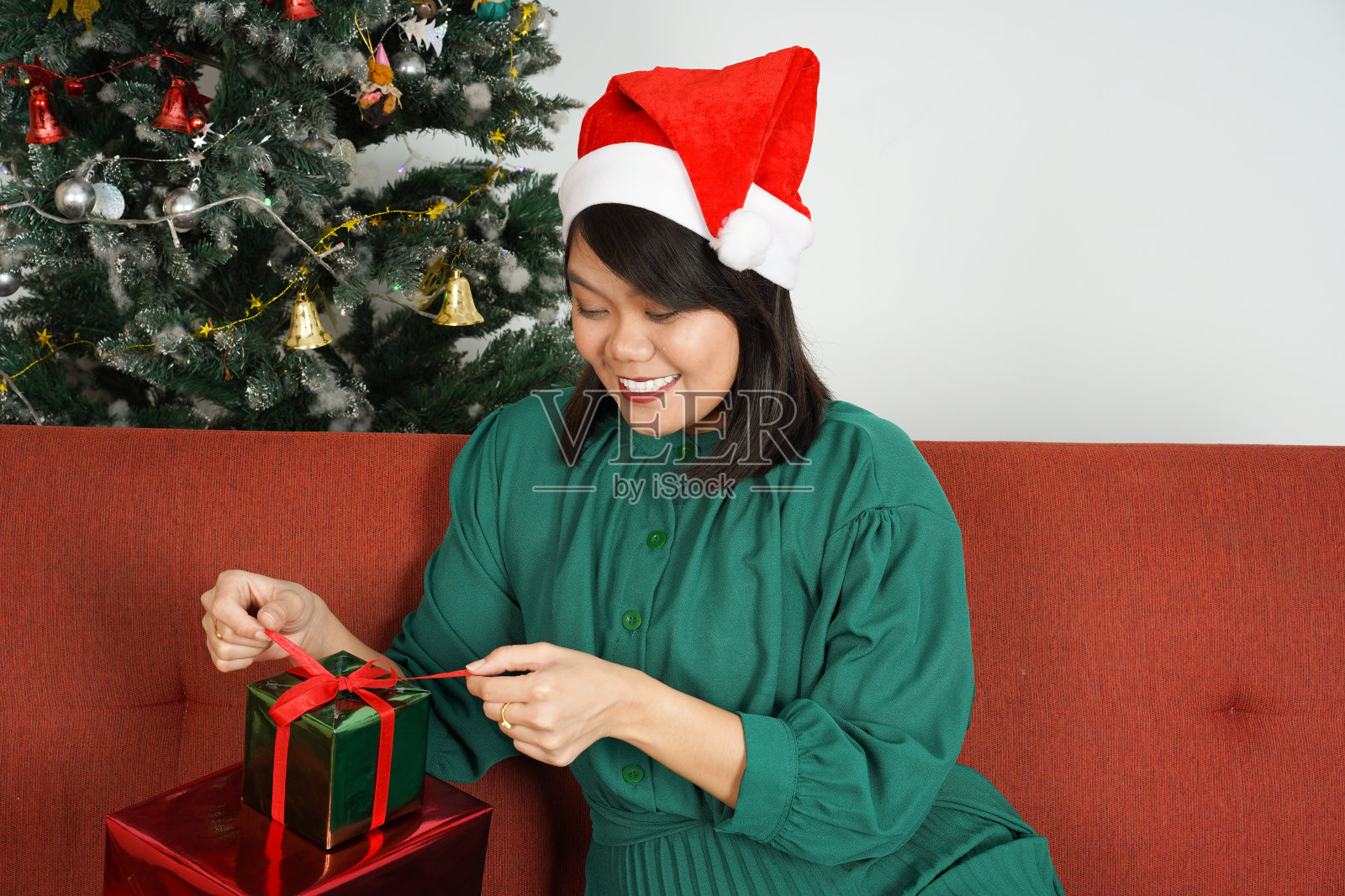 快乐美丽的亚洲妇女穿着绿色的裙子和圣诞帽，圣诞节庆祝，拿着圣诞礼物。照片摄影图片