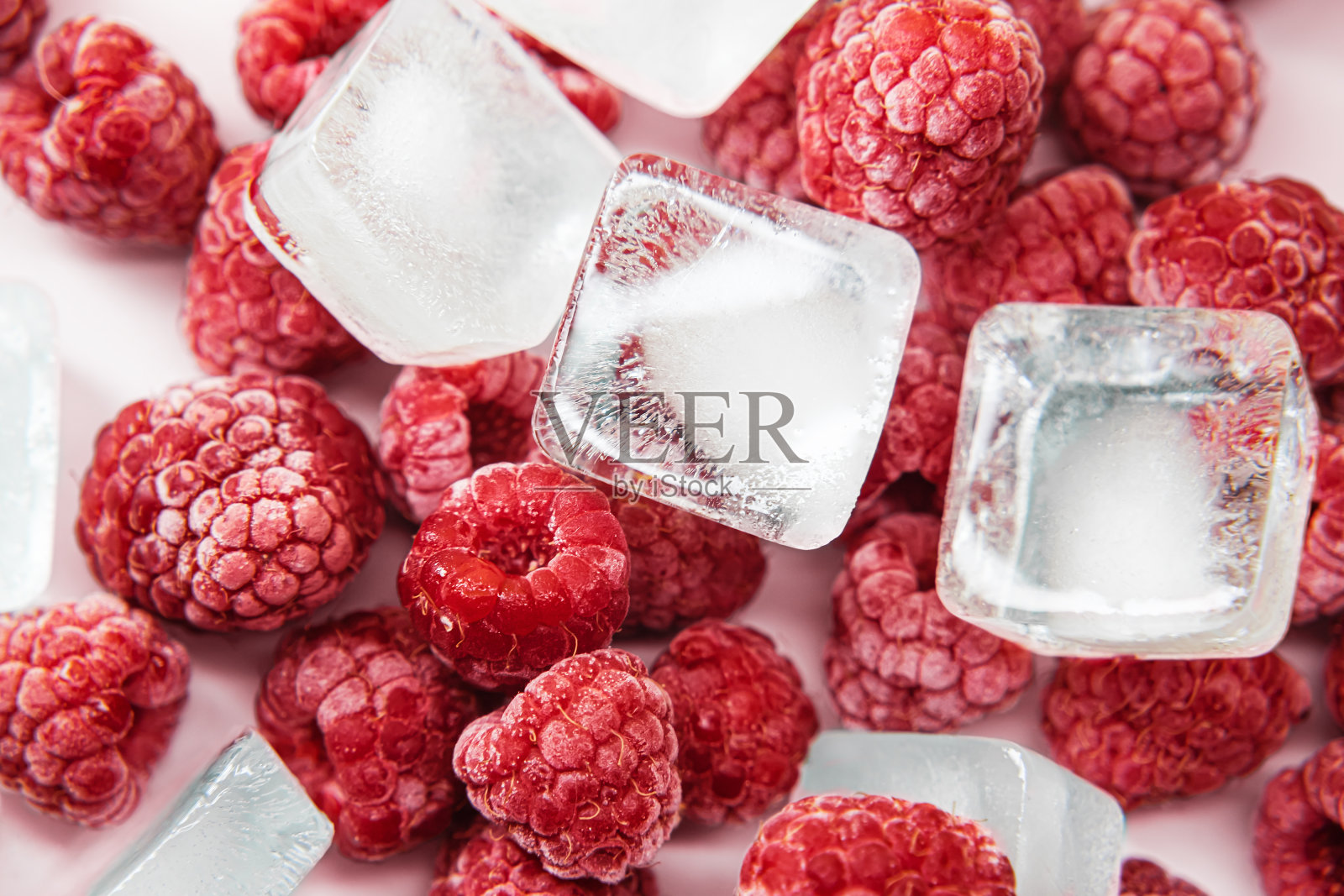 白盘子里的冰冻覆盆子。冻熟的覆盆子加冰块。生冻浆果。照片摄影图片