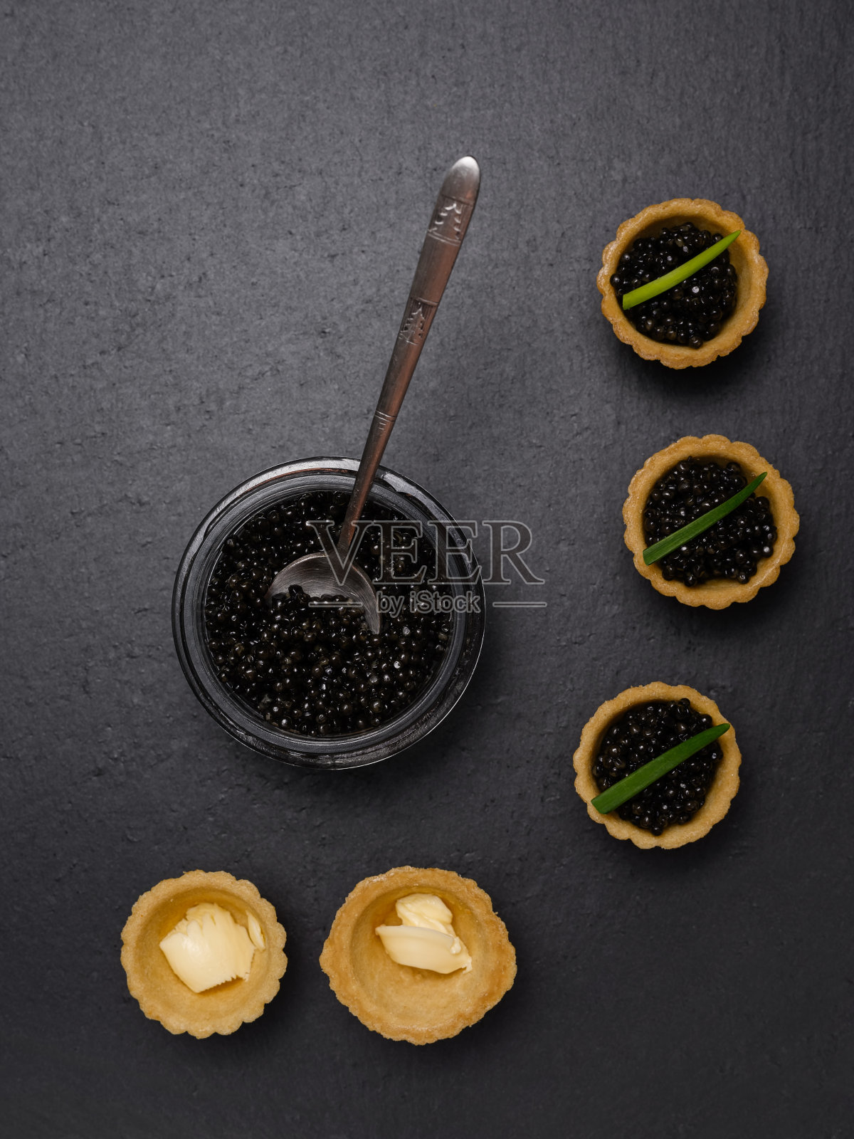 天然鲟鱼鱼子酱、奶油和青葱馅饼，铺在黑色石板上照片摄影图片