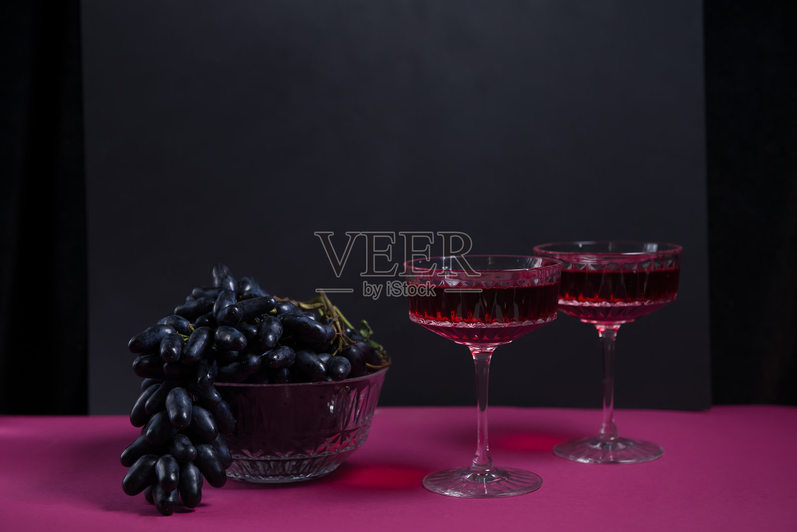 两个酒杯，一瓶红酒，一串黑葡萄。一个时尚、诱人的红酒广告。复制的空间。酒单。餐厅的广告。两人的浪漫晚餐。照片摄影图片
