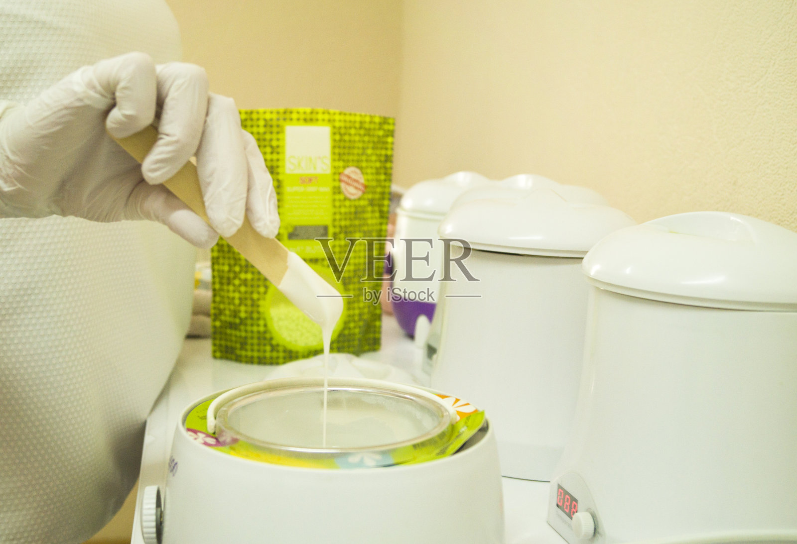 脱毛和美容的概念是用木铲去除毛发的膏体或蜡。明亮的绿色质量照片摄影图片