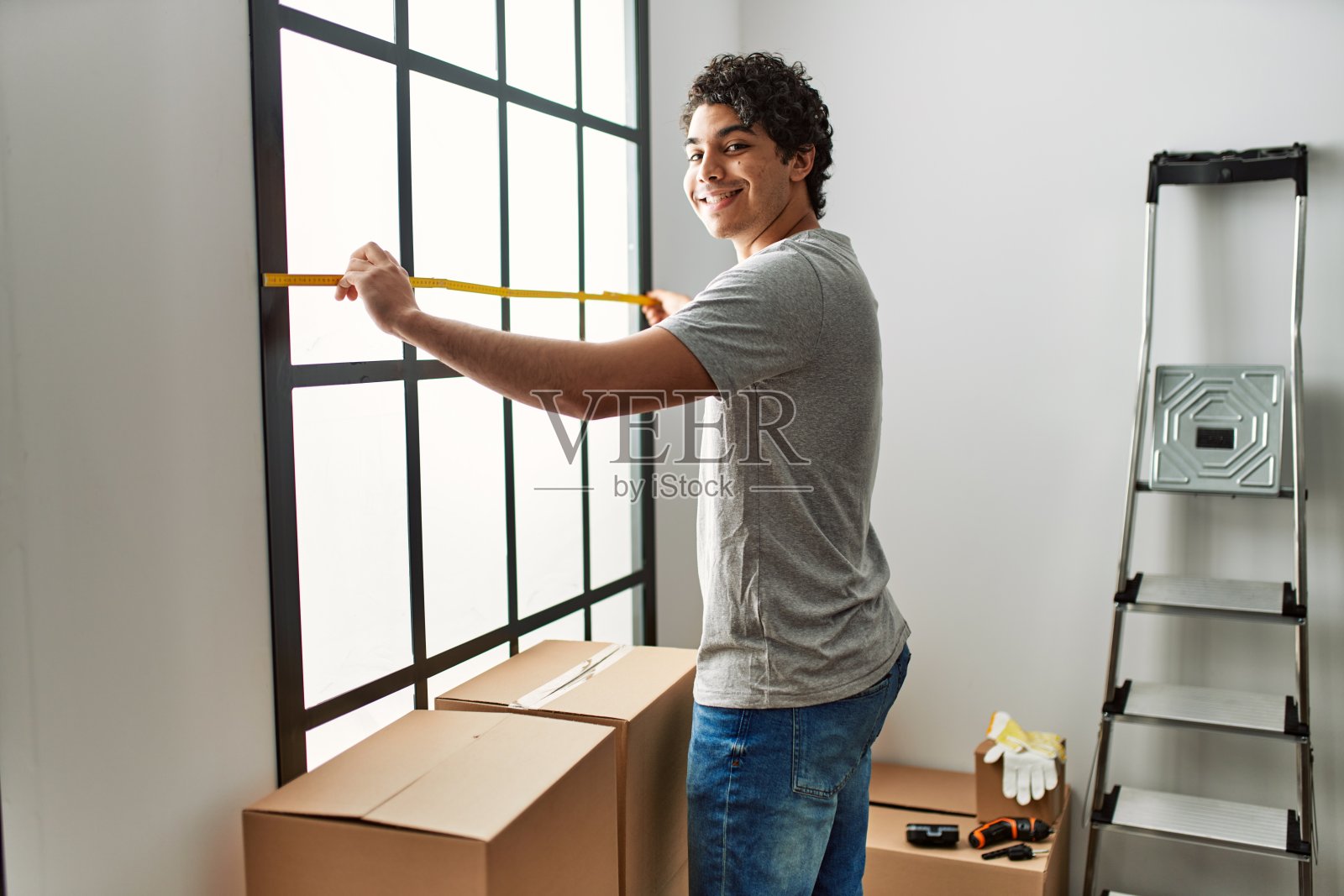 年轻的西班牙人微笑着愉快地搬到新家。照片摄影图片