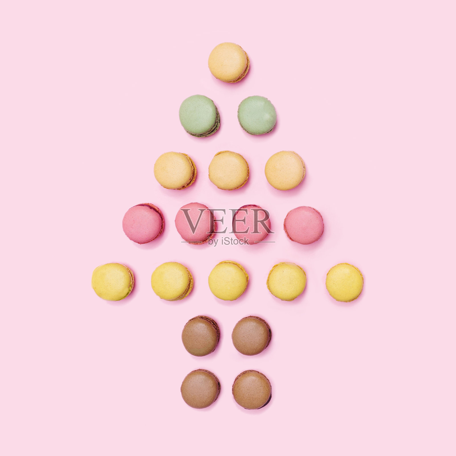 圣诞树激发了最小的概念。不同颜色的手工马卡龙排列。平铺，淡粉色背景。照片摄影图片