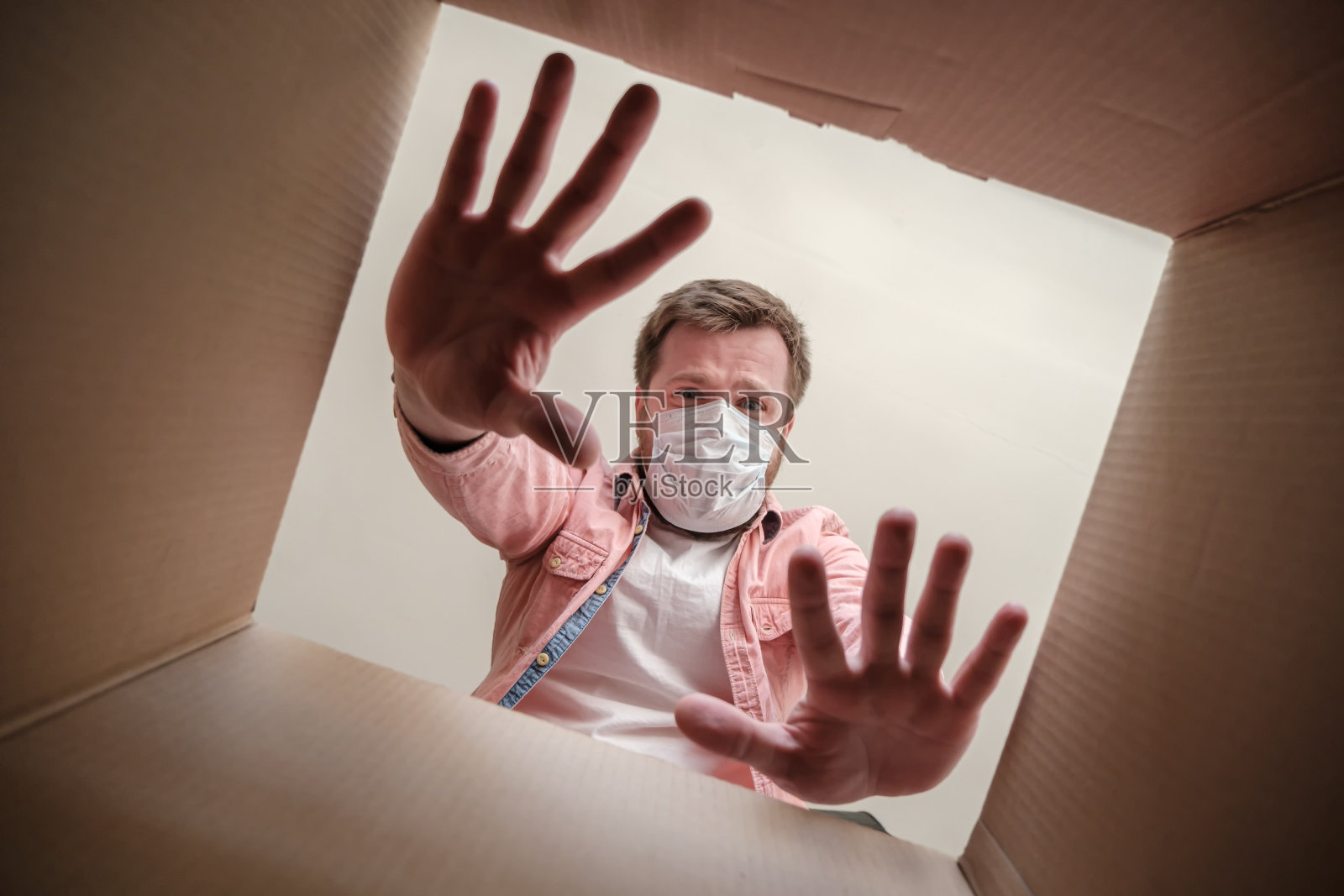 一名戴着医用口罩的男子在打开一个投递箱时，用害怕病毒的手做出了停止的手势。偏执狂。照片摄影图片