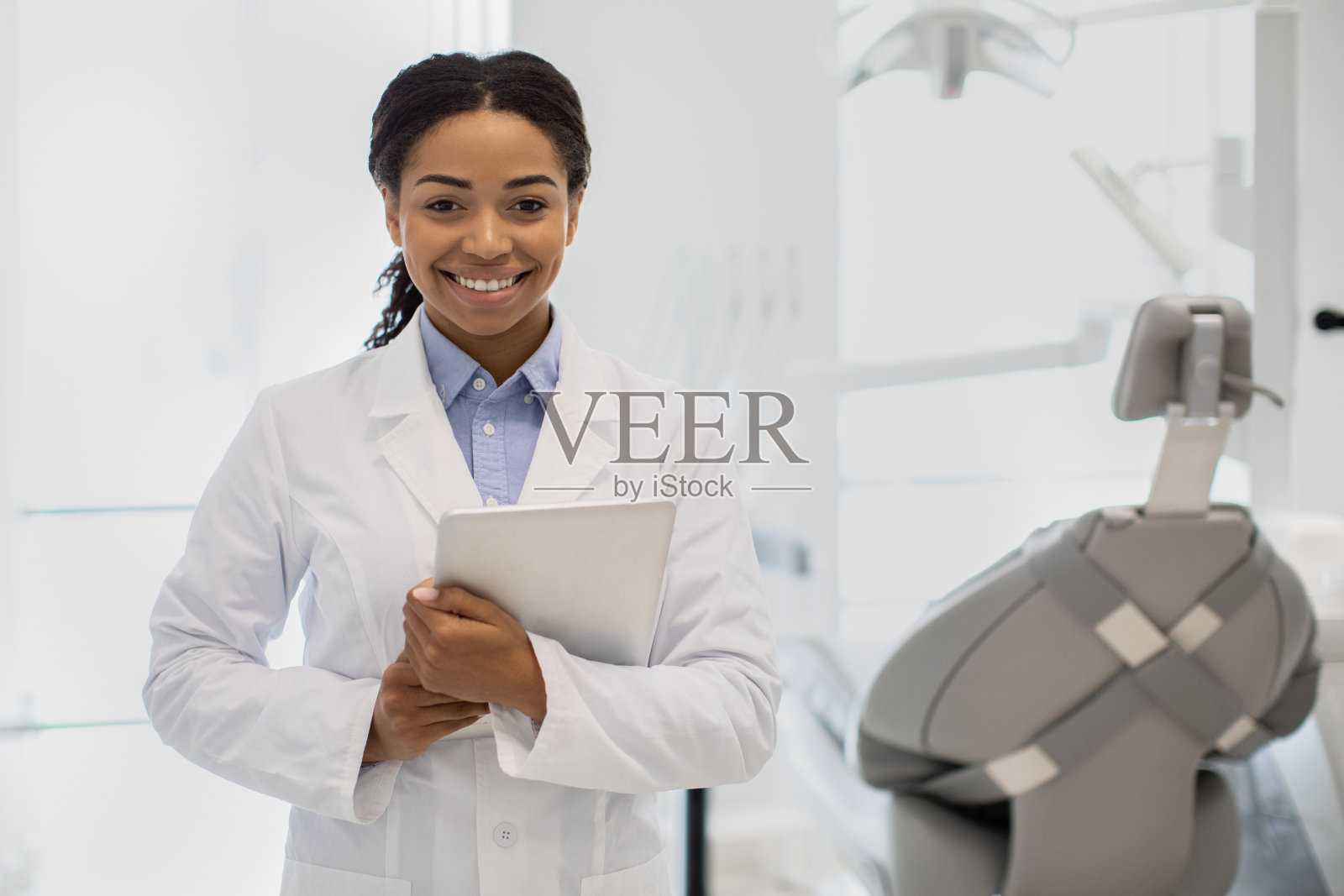 专业的牙医。黑色口腔医生女士的肖像与数码平板在手中照片摄影图片