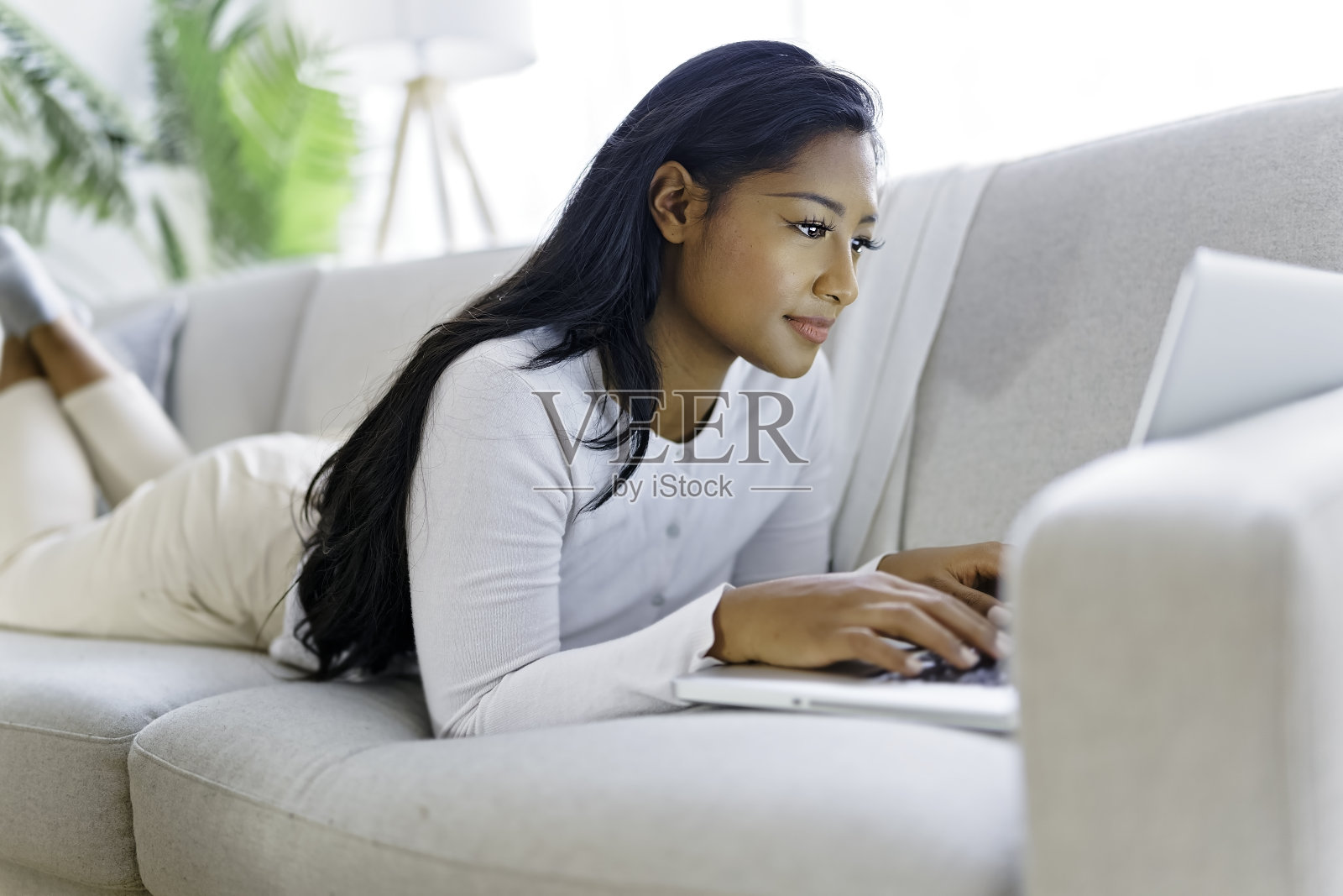 年轻女子在舒适的沙发上使用笔记本电脑照片摄影图片