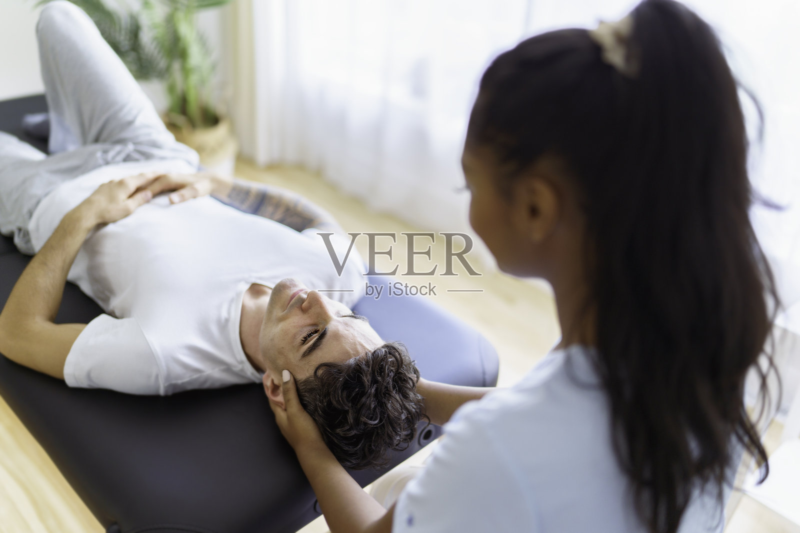 年轻女性物理治疗师在物理诊所与客户照片摄影图片