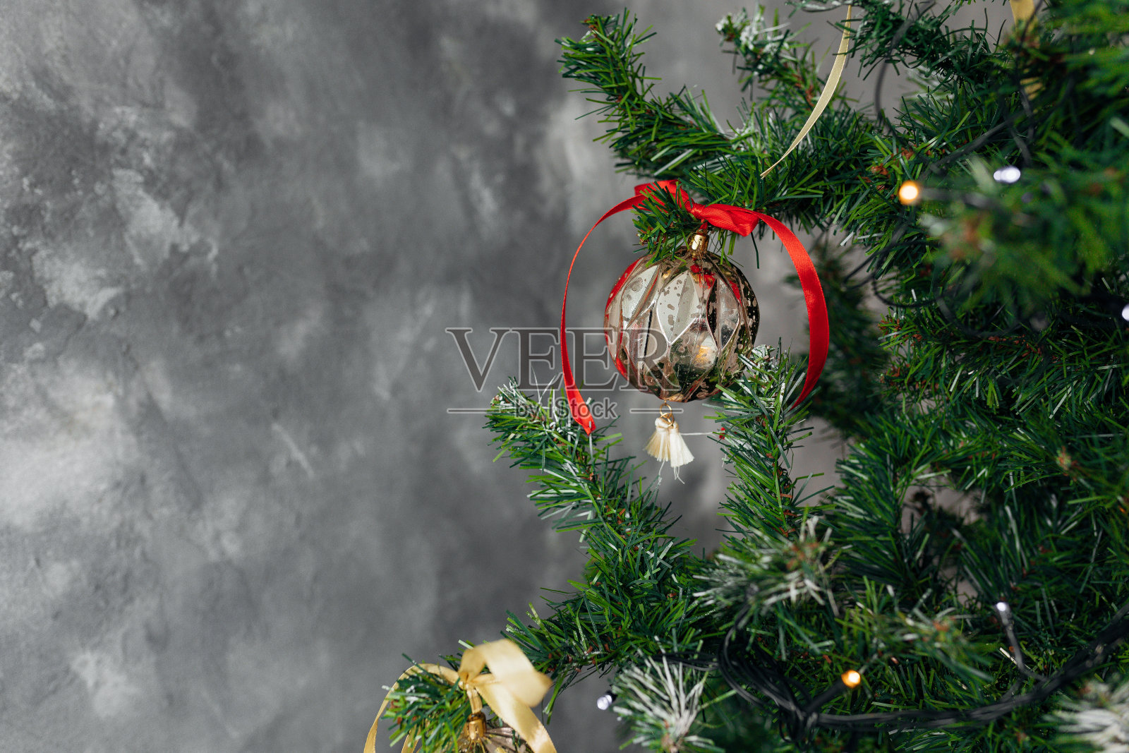 圣诞节的背景。副本的空间。有圣诞球的云杉和松树的树枝。节日前夕。新年。红色金色装饰在灰色混凝土墙的背景上。照片摄影图片