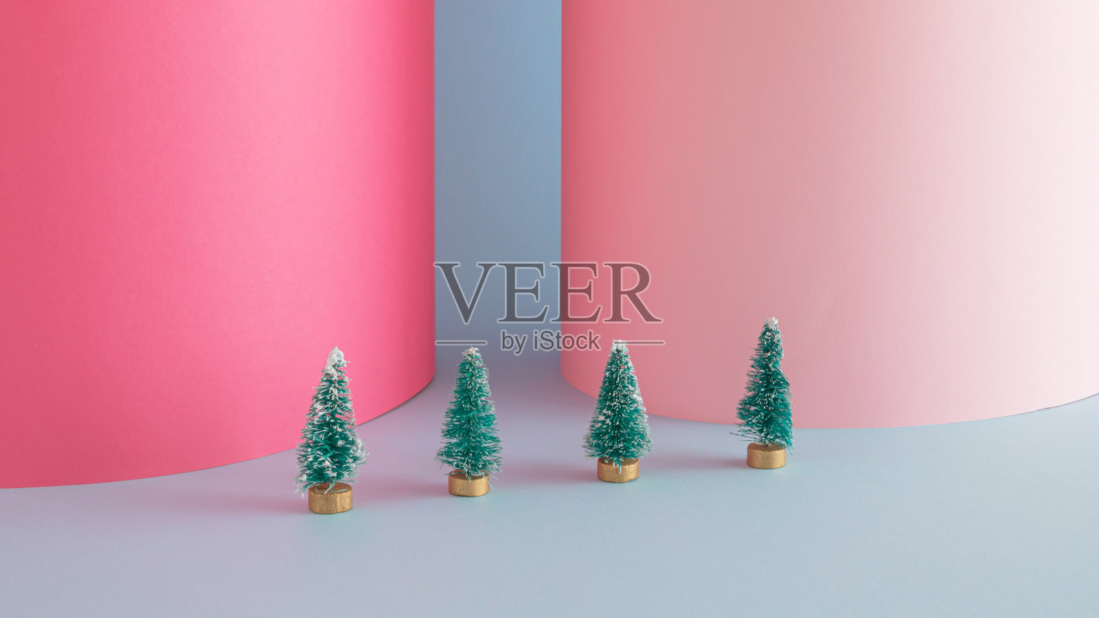 在蓝色和粉红色的背景上有圣诞树的创意圣诞布置。最小的 新年的概念。照片摄影图片