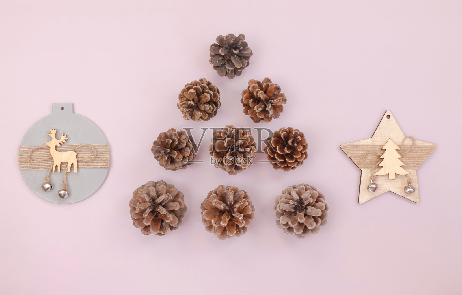 圣诞树由松果和木制装饰在淡粉色背景，俯视图照片摄影图片