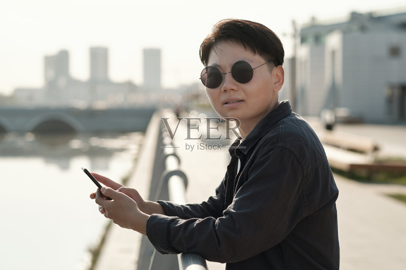 年轻的中国女商人戴着墨镜站在河边照片摄影图片