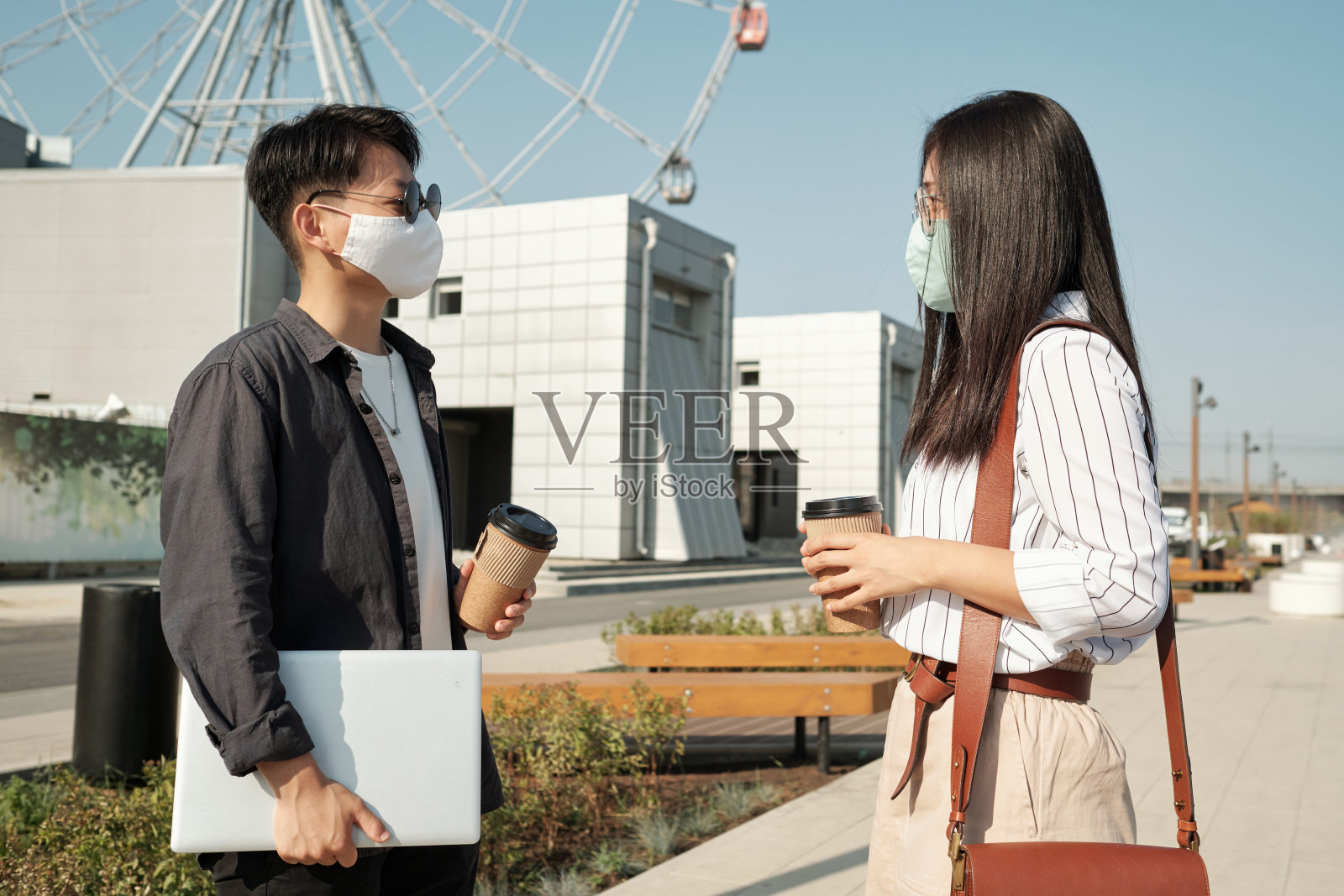 两个戴着防护口罩的年轻同事面面相觑照片摄影图片