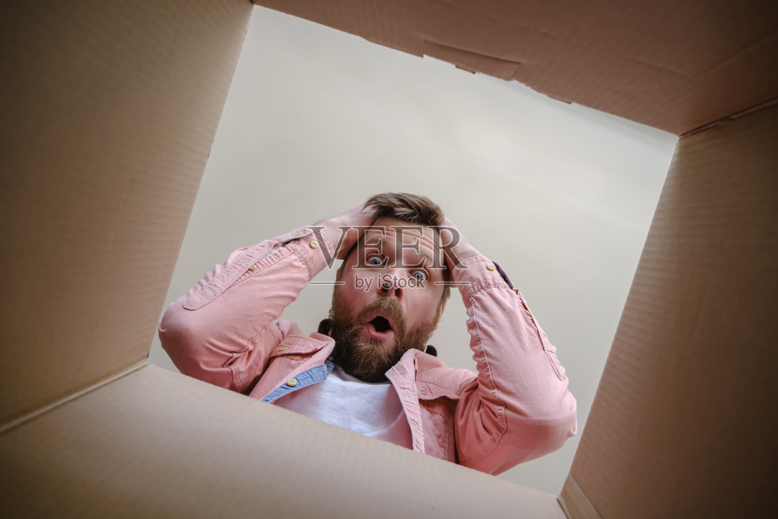 一名男子震惊地在一个未包装的快递箱内发现了错误的订单，他很沮丧，用手抓住了头部。拆箱内部视图。照片摄影图片