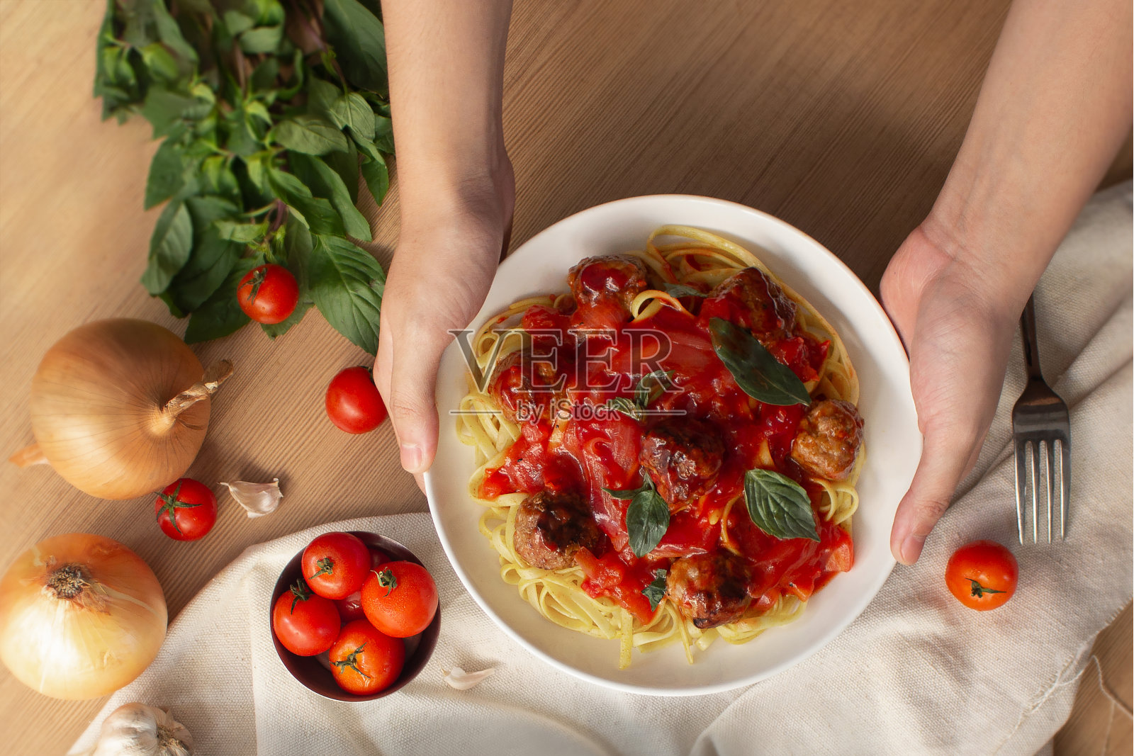 手拿着意大利面，背景中有生食材照片摄影图片