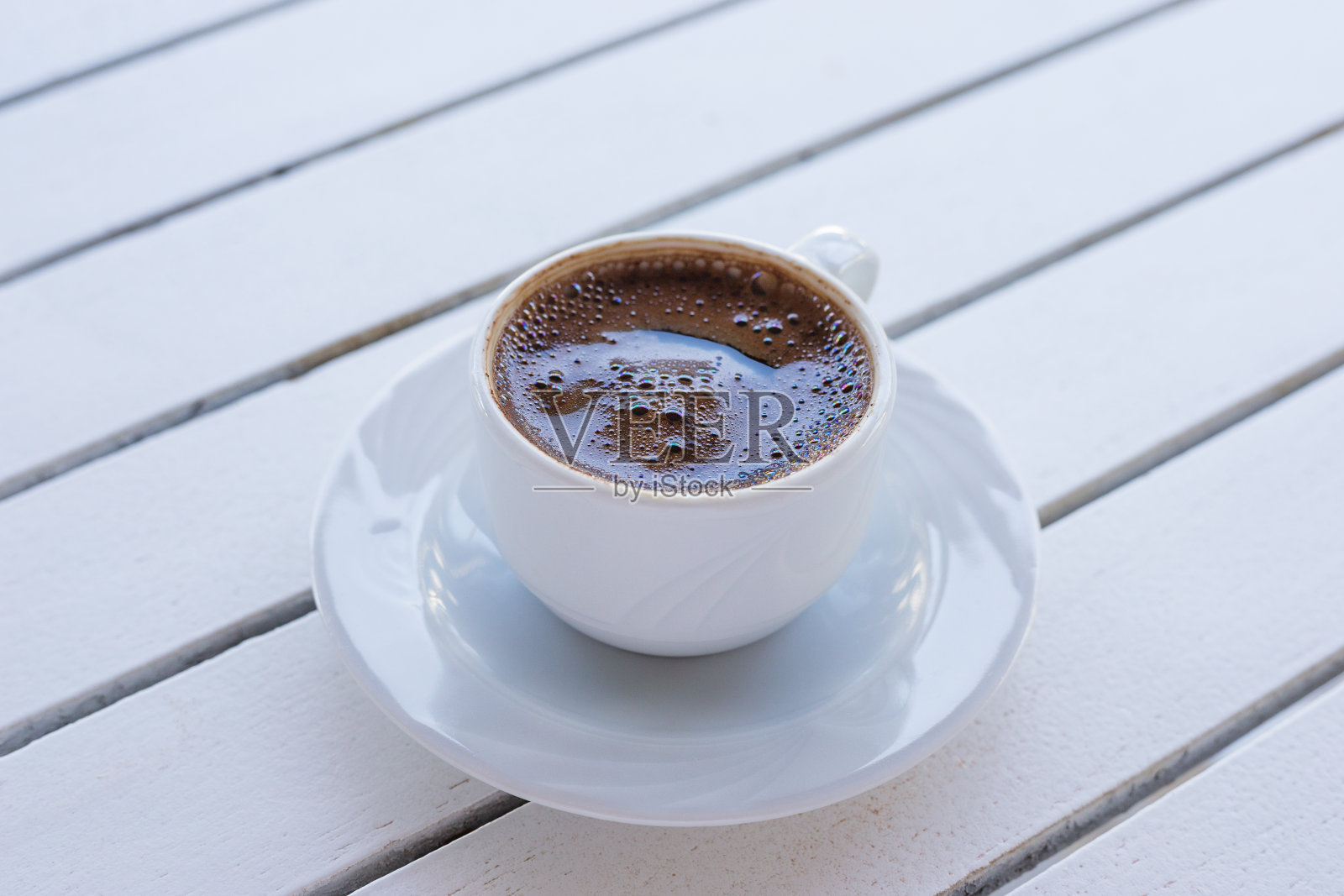 白色的土耳其咖啡杯放在浅木桌上的碟子上。生活方式的背景。等距的风格。照片摄影图片