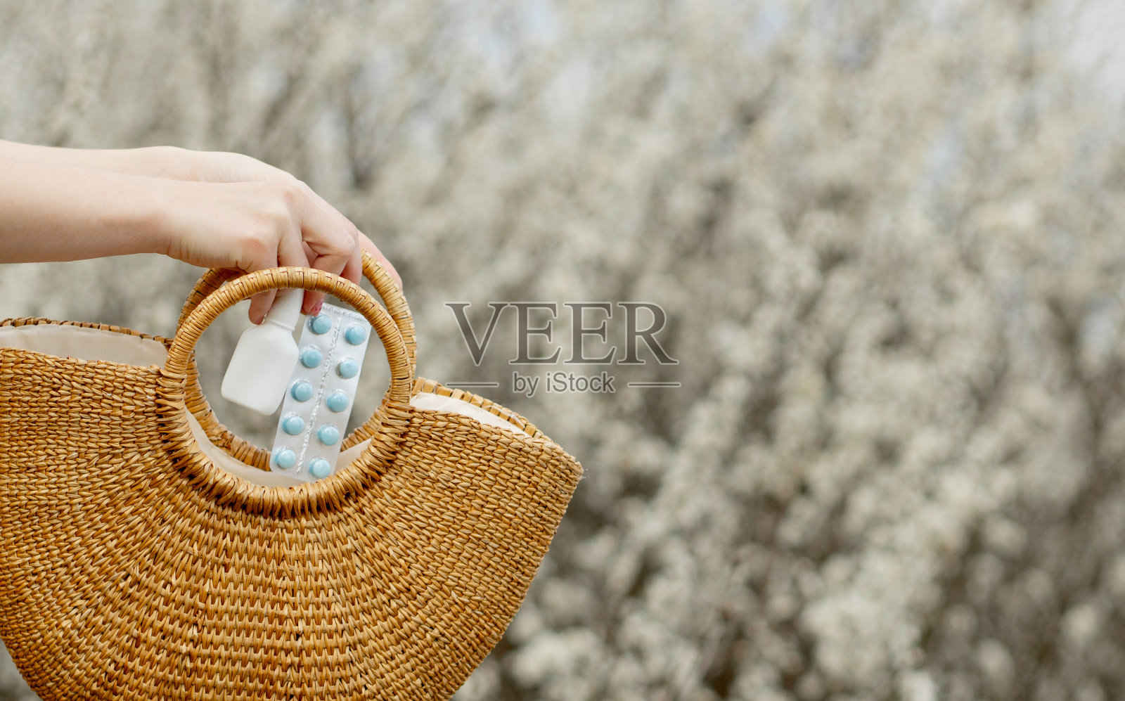 女人的手把过敏药放在袋子里，在开花的背景照片摄影图片