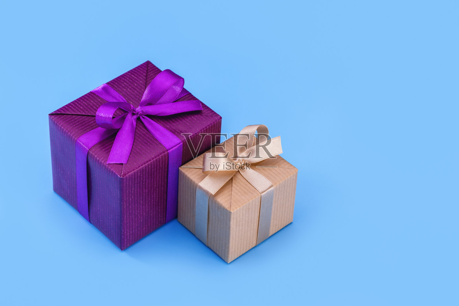 两个盒子里装着礼物，精美的包装上有丝带和蝴蝶结。蓝色背景，复制空间。照片摄影图片