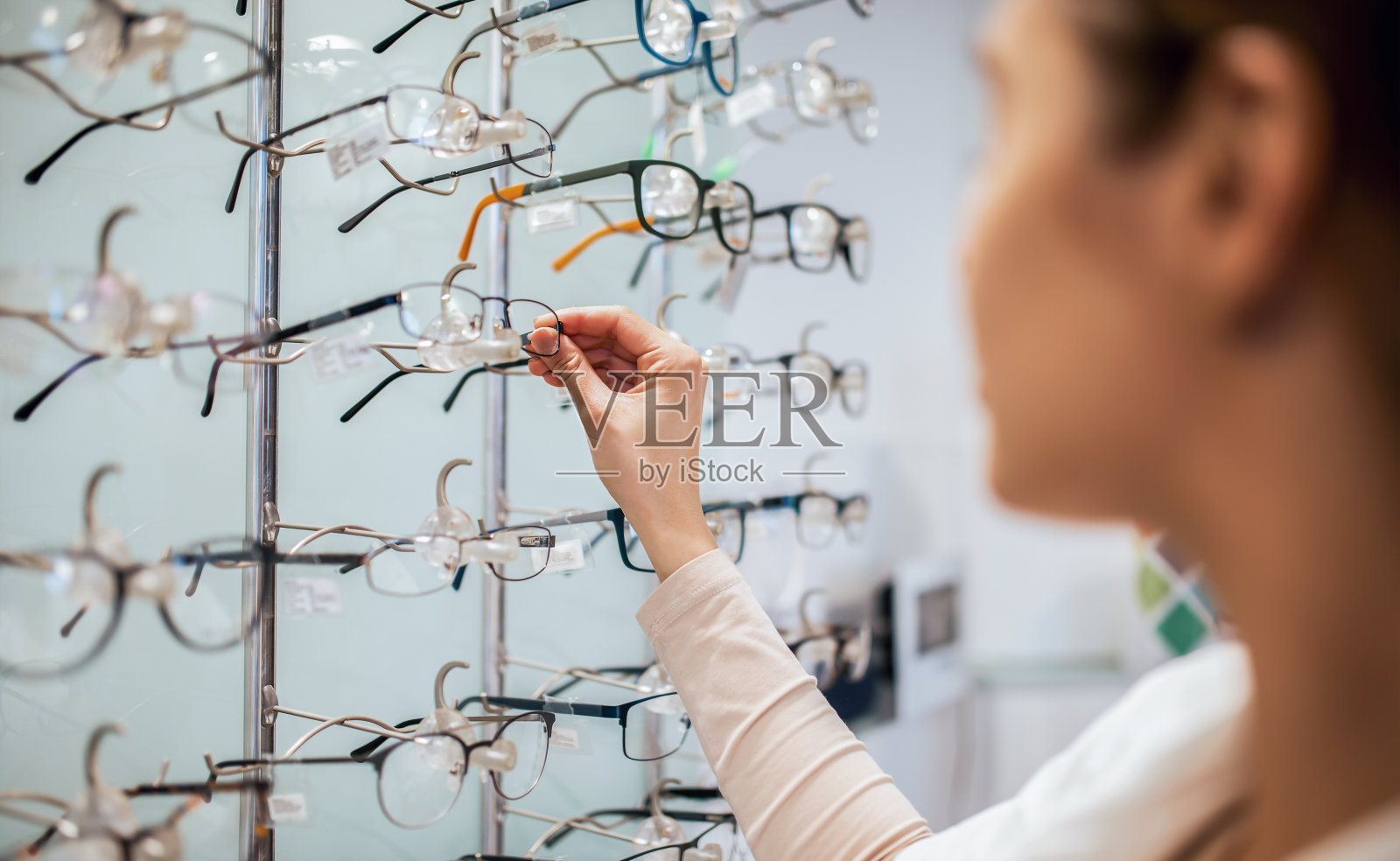 年轻女子在光学商店选择新的眼镜，近距离照片。医疗、保健理念照片摄影图片