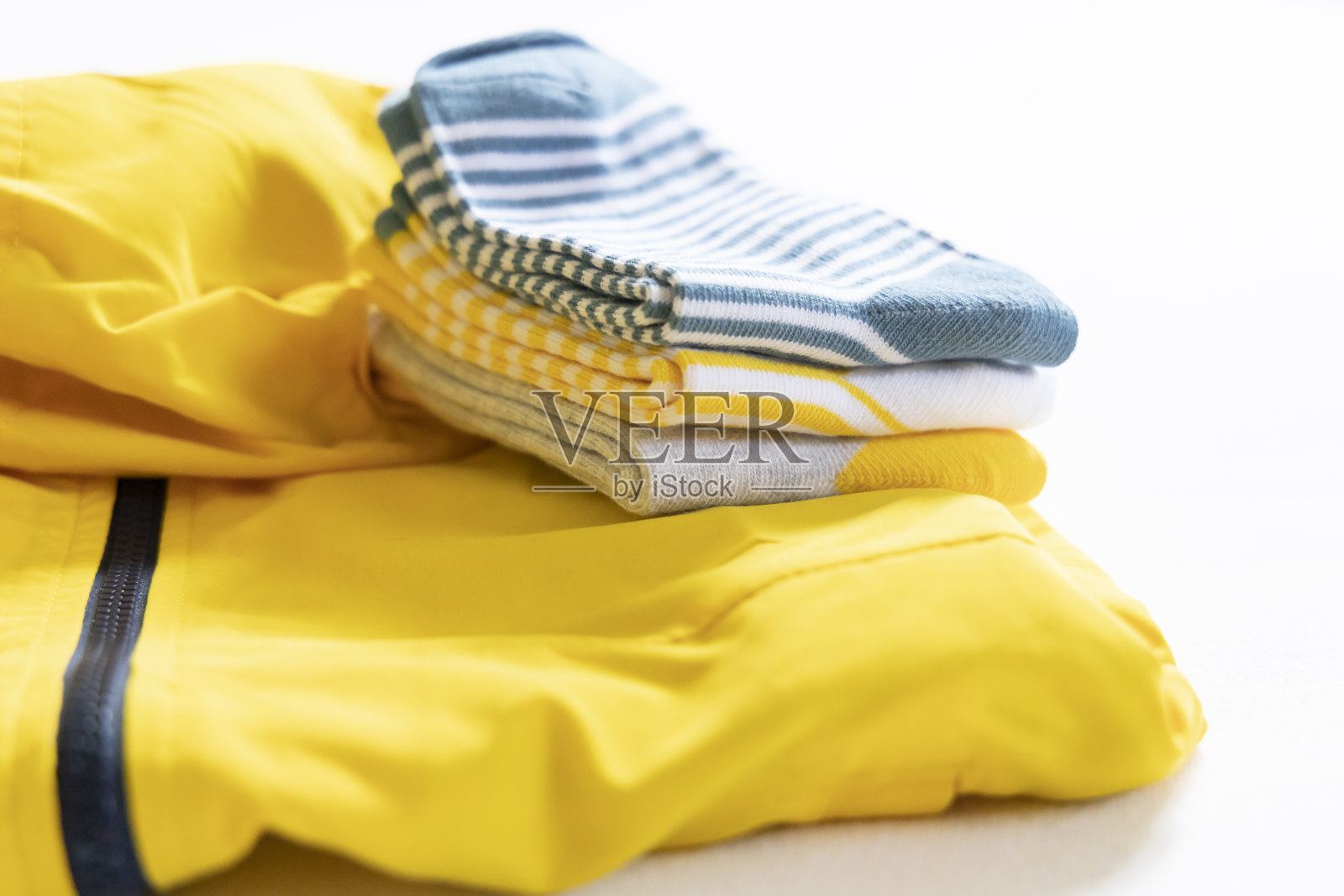 黄色婴儿夹克和一套黄色袜子整齐地叠在一起。黄色的衣服。黄色在日常生活中无处不在。照片摄影图片