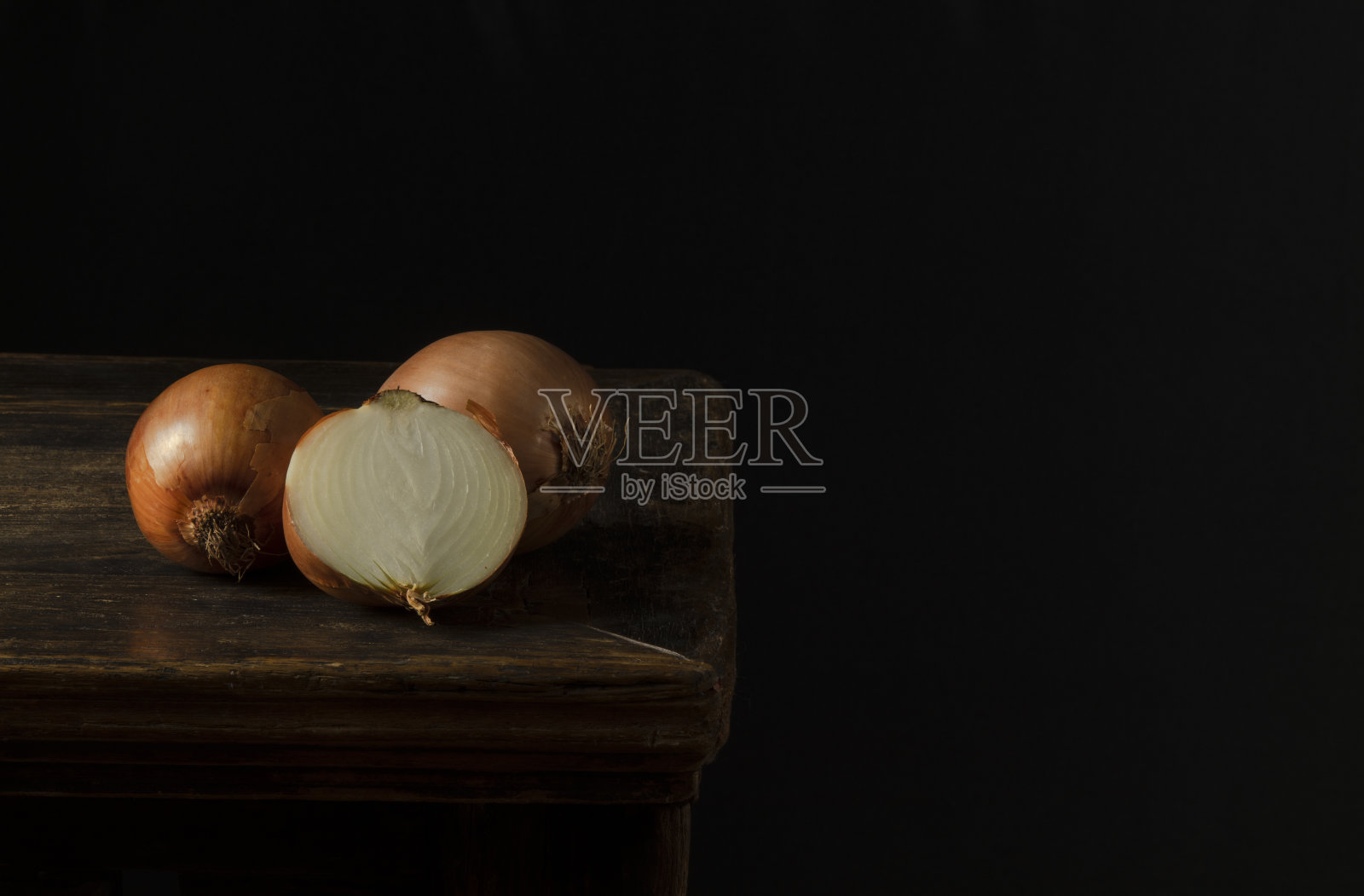 黑色背景下木桌上的洋葱静物画照片摄影图片