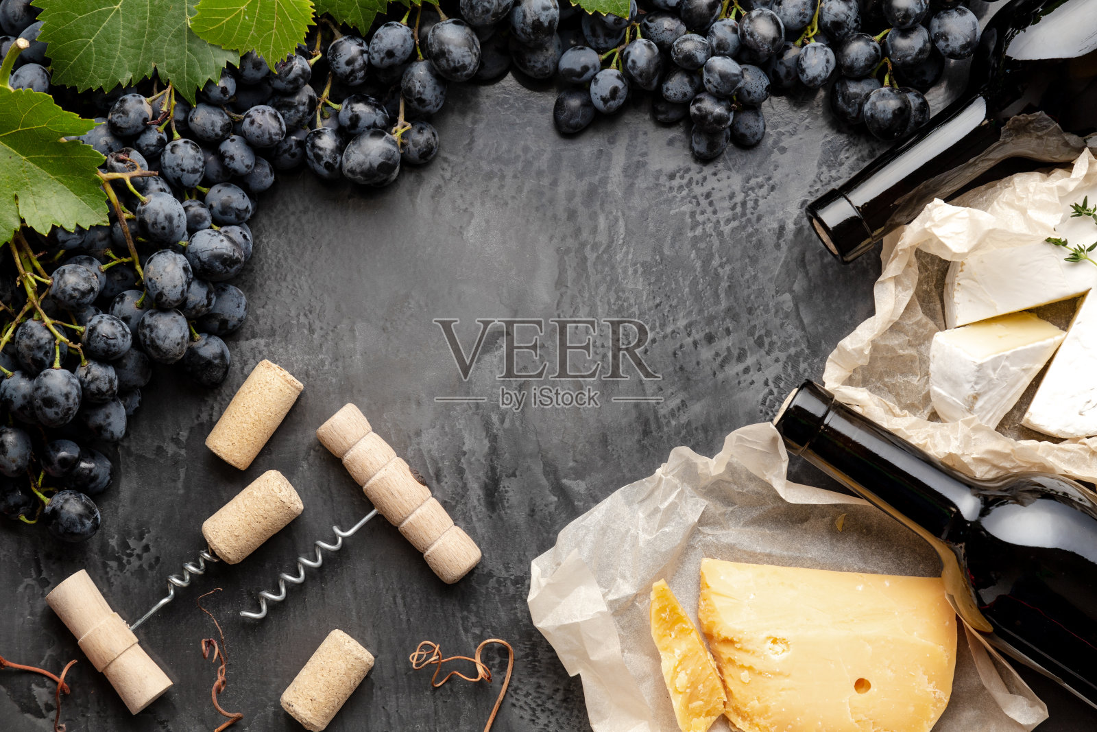 酒瓶，奶酪，葡萄，开瓶器，框架。佳酿的静物葡萄酒搭配卡门贝尔葡萄。餐厅晚餐，深色混凝土背景下品酒。空间的文本照片摄影图片