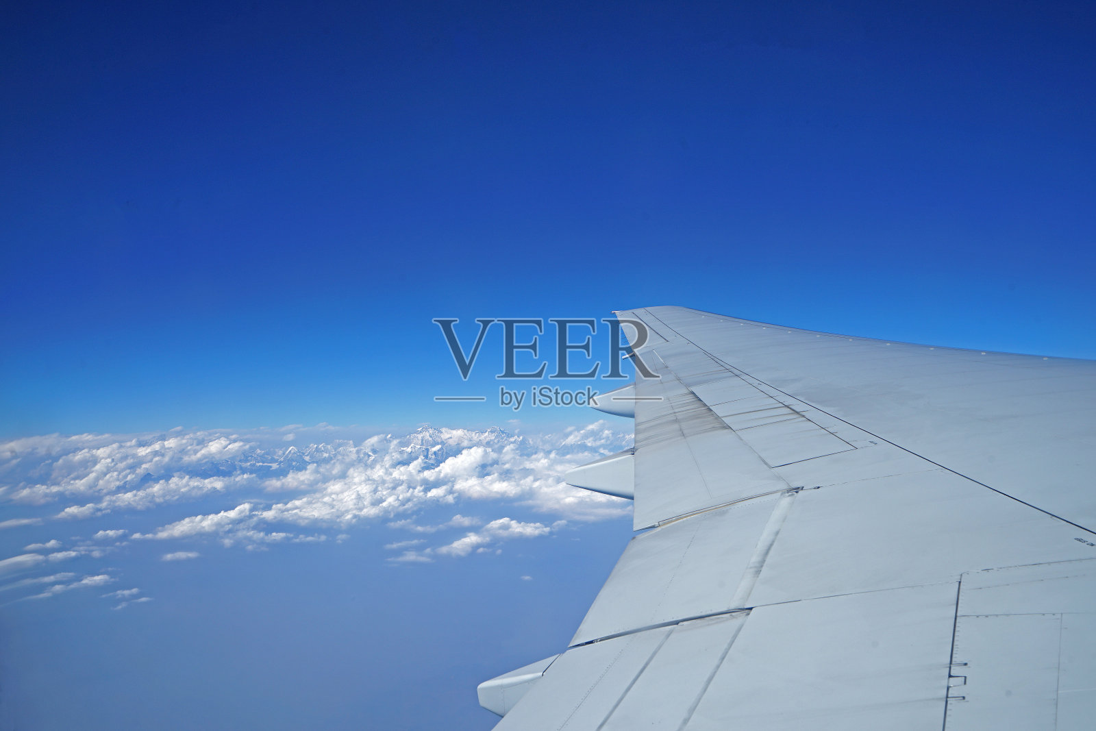 飞机机翼与珠穆朗玛峰喜马拉雅山范围的视野和多云的蓝天照片摄影图片