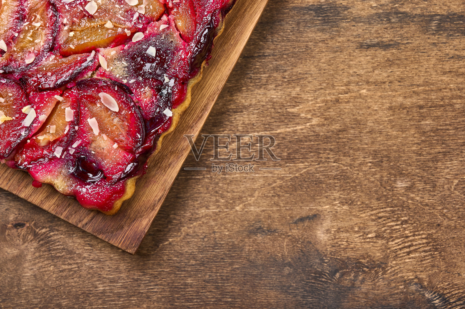 在乡村背景的木制砧板上放有李子的馅饼或派照片摄影图片