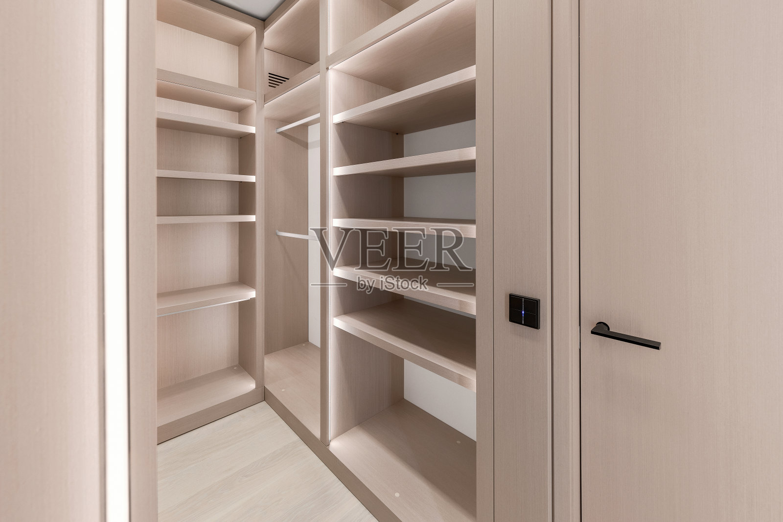壁橱柜内的木制货架上有LED照明，衣柜柜内的垂直和水平条形LED灯。现代简约的衣柜内部照片摄影图片