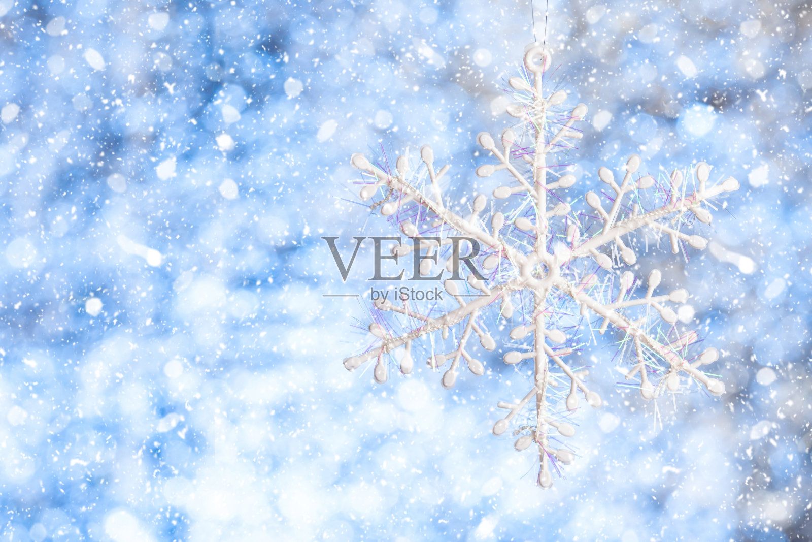 雪花在雪中。白色的雪花模糊闪亮的白蓝色背景。副本的空间。模板设计照片摄影图片