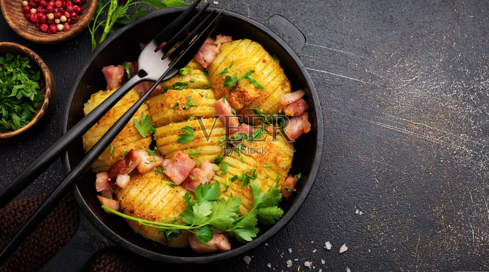 烤土豆配火腿、香草和面包屑在深色的背景上。北欧美食。前视图。照片摄影图片