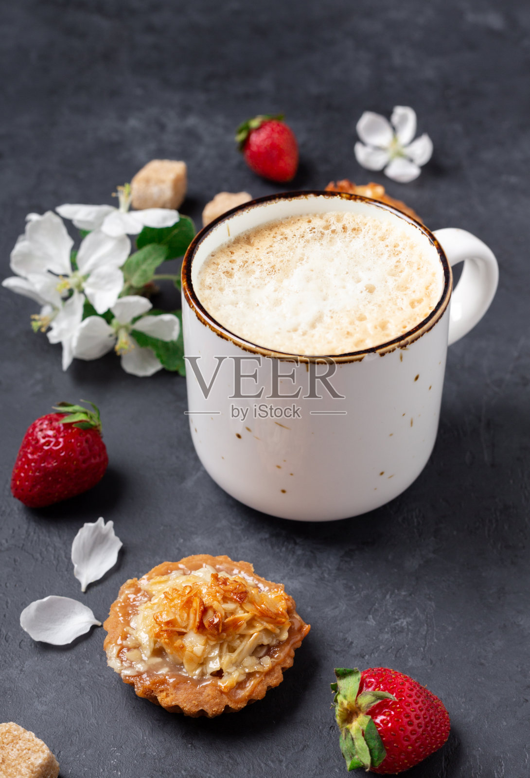 一杯咖啡，蛋糕和春天的花朵在深色的石头背景照片摄影图片