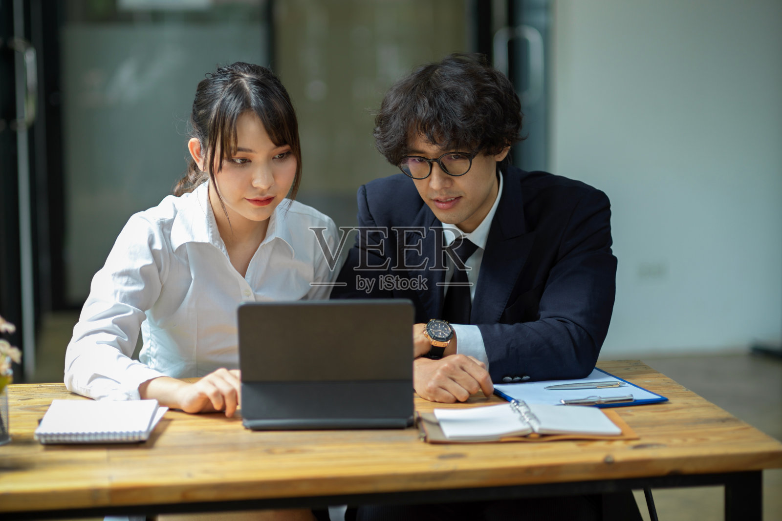 一位亚洲同事在办公室用数码平板电脑工作。照片摄影图片