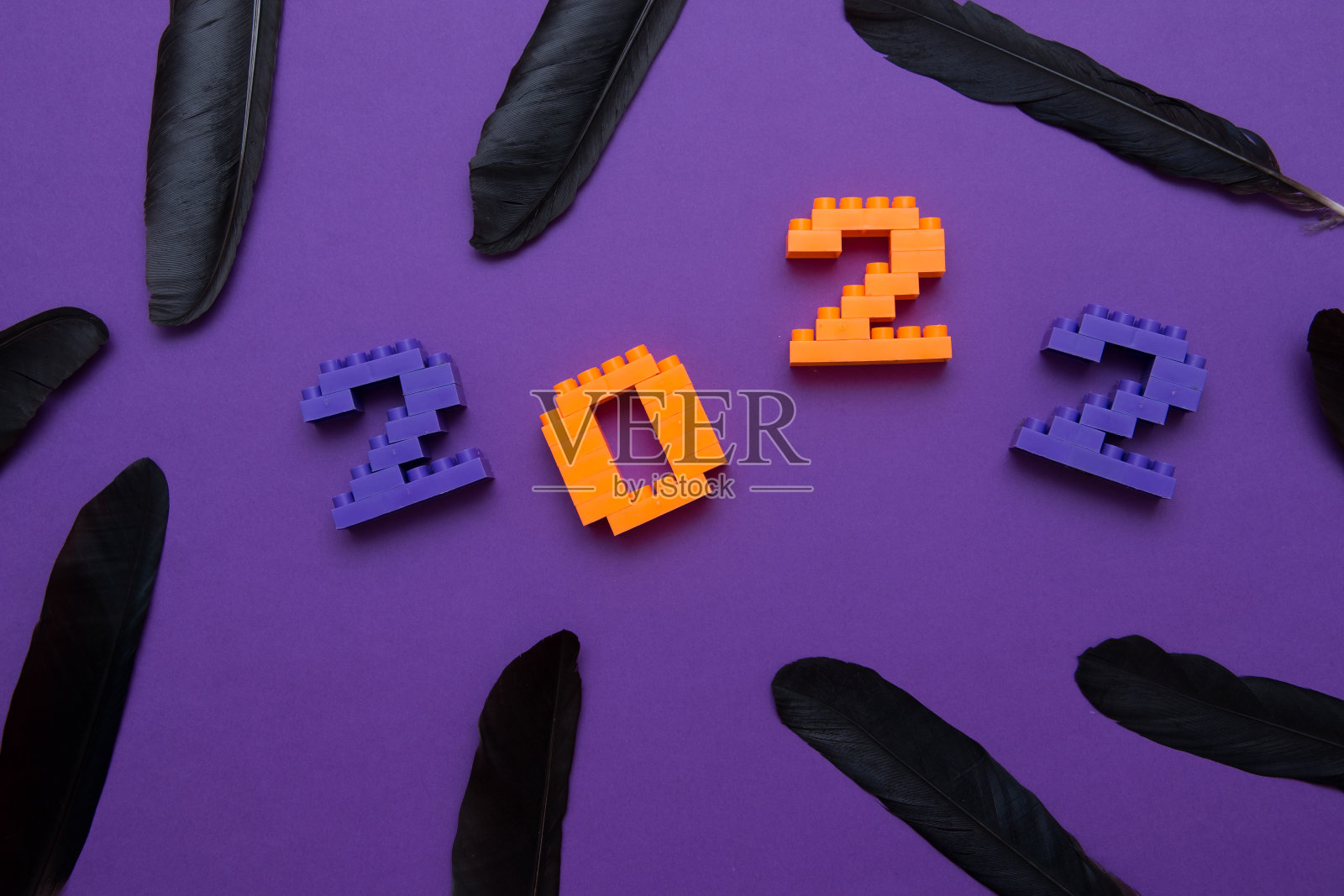 儿童设计师设计的数字2022，紫色背景上的黑色乌鸦羽毛。照片摄影图片