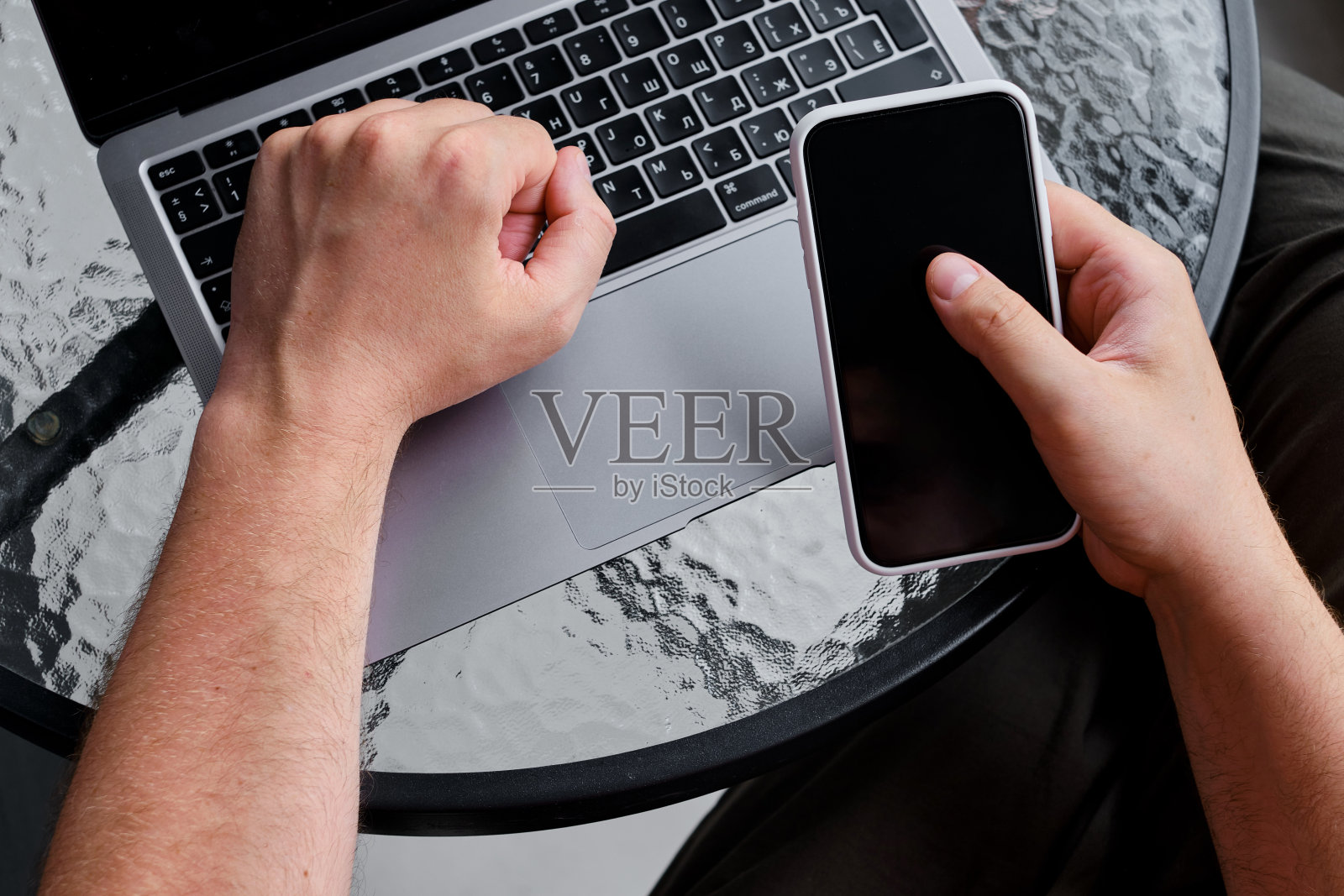 一个男人在桌上用笔记本电脑和智能手机工作。远程办公，办公空间。商人在办公室里工作。商业背景。家庭办公室照片摄影图片