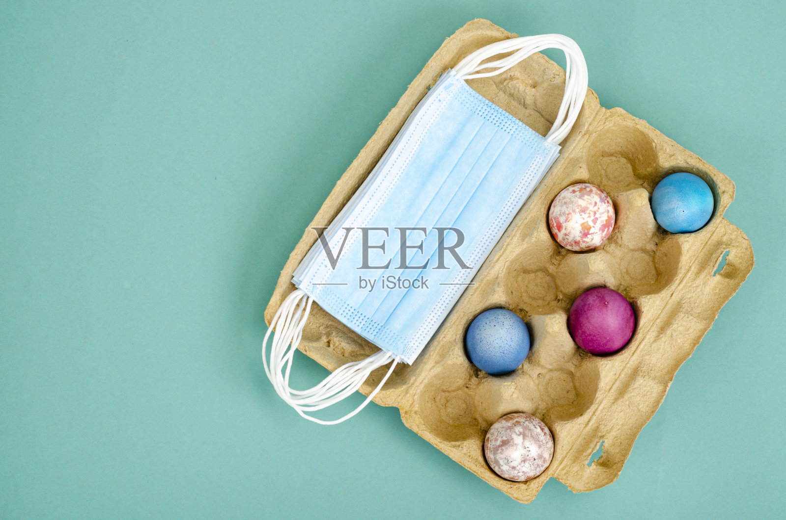 复活节隔离的概念装饰蛋和白色的保护面具在明亮的背景。社会距离照片摄影图片