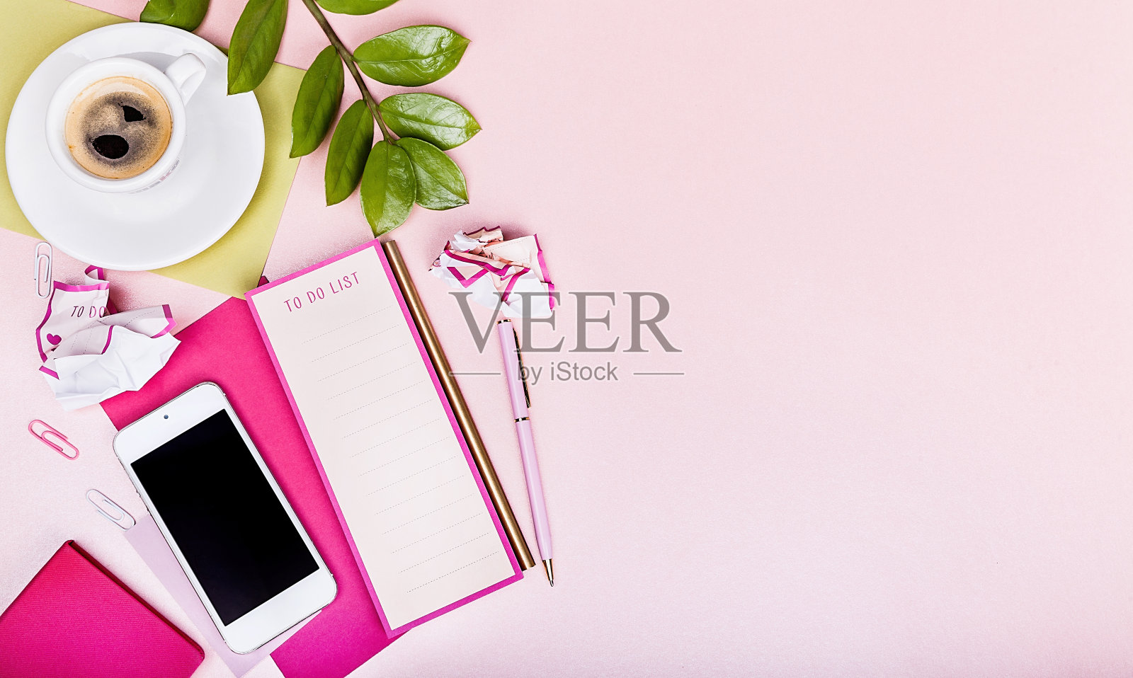 平板上有记事本，智能手机，待办事项清单，笔，一杯浓咖啡，绿叶，粉色背景照片摄影图片