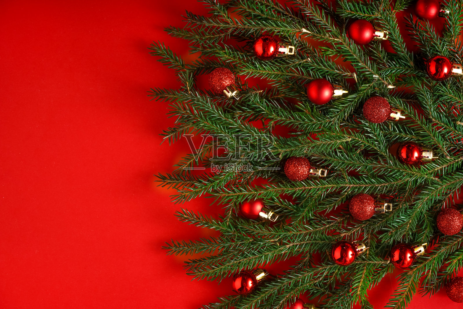 红色背景下的绿色针叶树枝做成的圣诞树。圣诞节背景与地方的文本。圣诞假期的概念。球玩具。本空间照片摄影图片