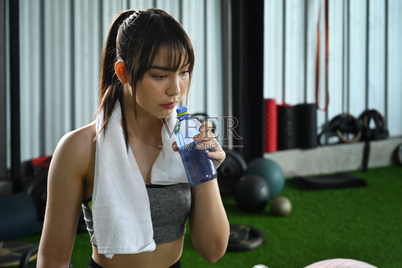 健身女喝水，健身训练后在健身房休息。照片摄影图片