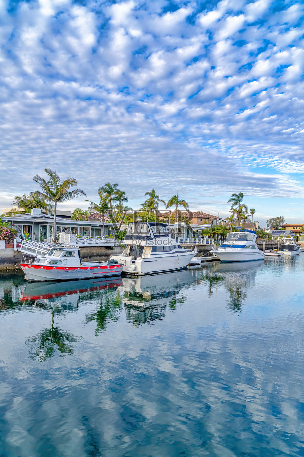 蔚蓝的天空和云朵倒映在海上，还有私人码头和船只照片摄影图片
