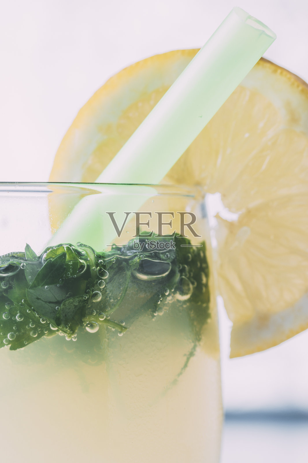 在蓝色大理石桌子上，有一杯柠檬水和香草，柠檬从底部切下来。照片摄影图片