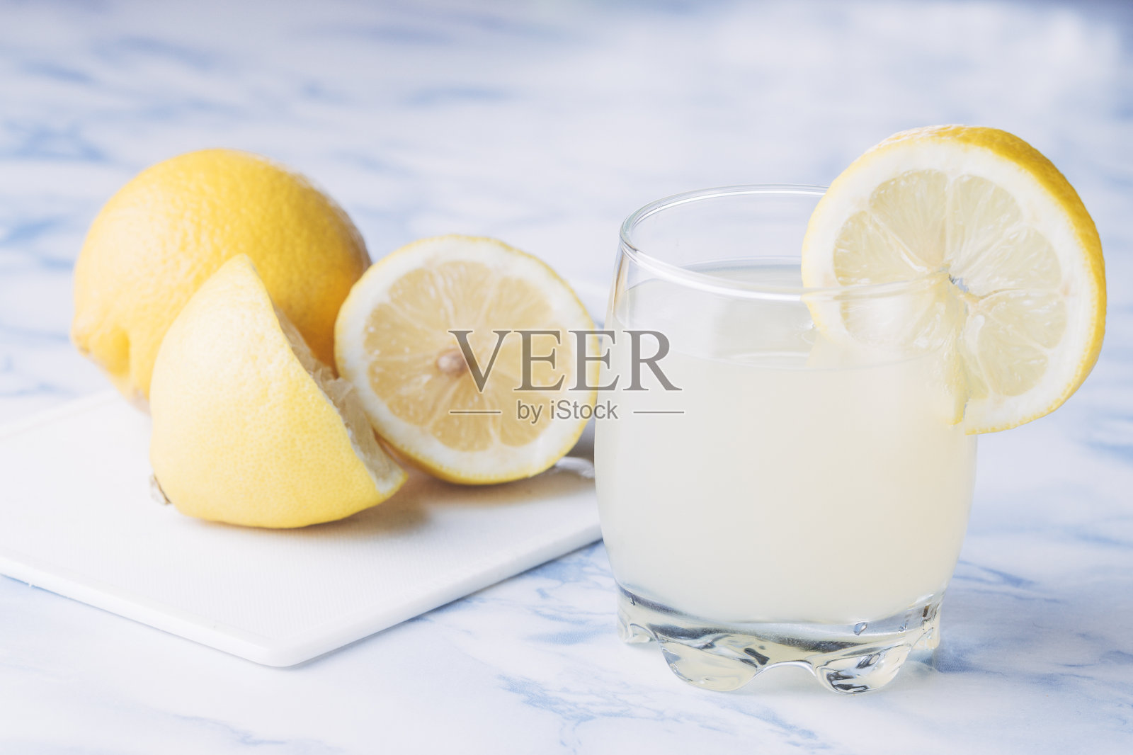 蓝色大理石桌子上放着一杯柠檬柠檬汁。照片摄影图片