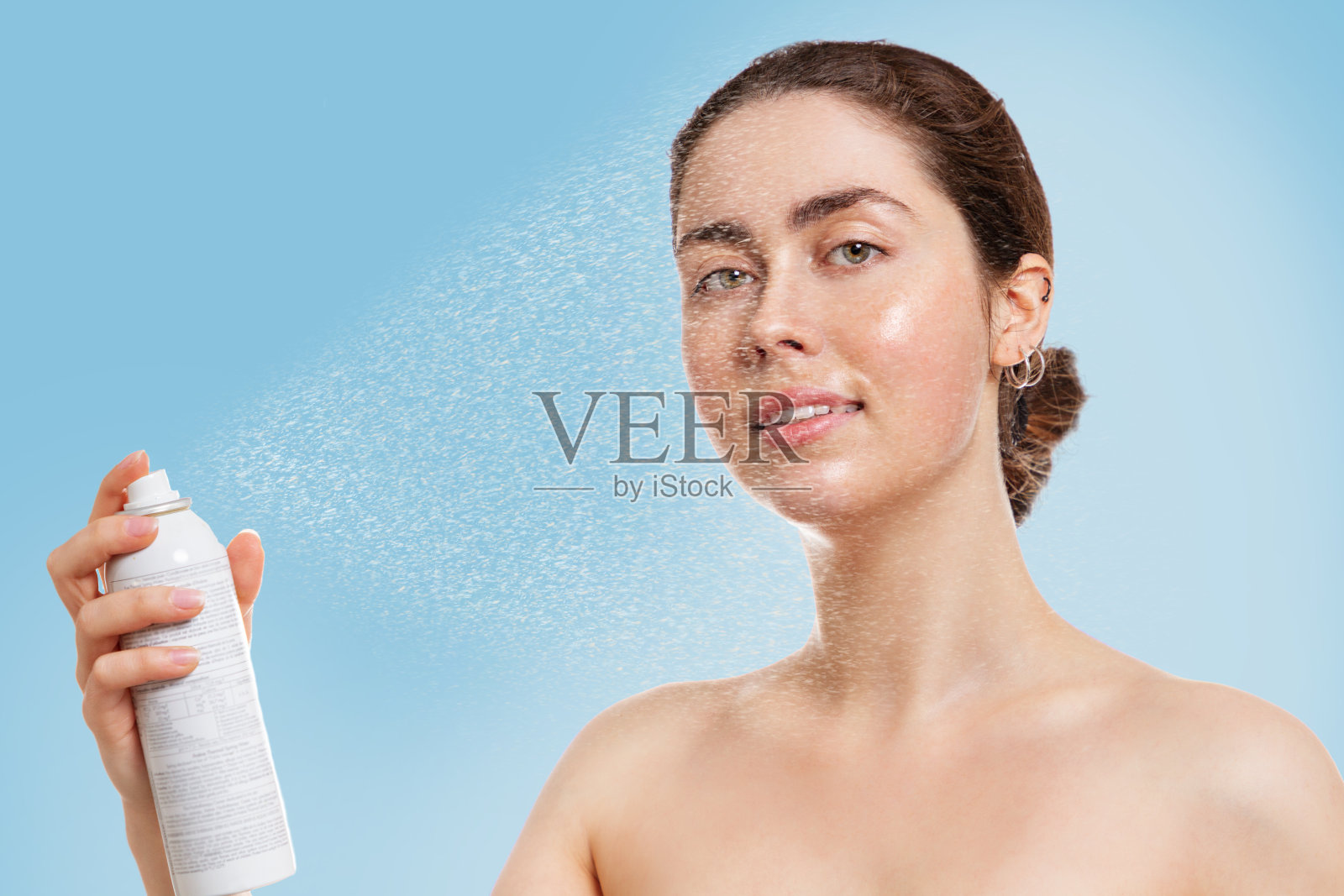 年轻的白种人女人的肖像与湿皮肤溅热水在她的脸。蓝色背景。美容、护肤、保湿的概念照片摄影图片