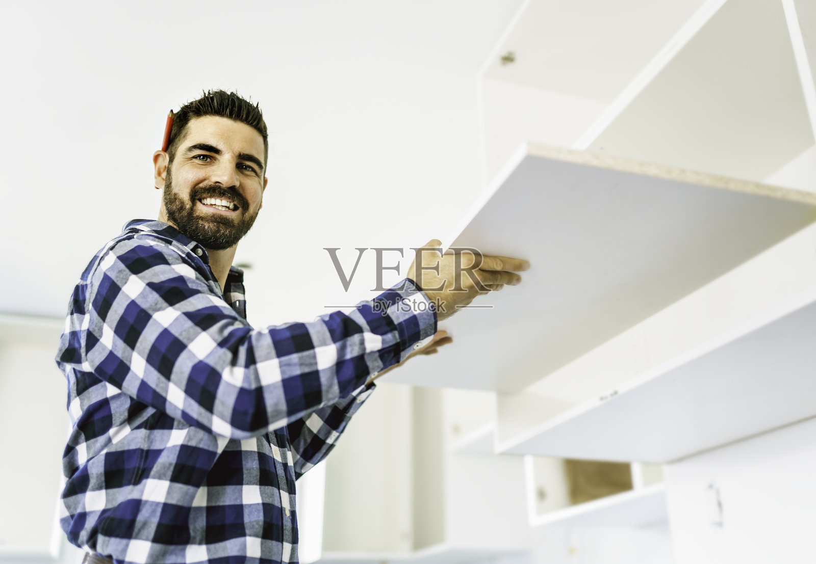 全神贯注的年轻人在厨房里摆弄着白色的橱柜照片摄影图片