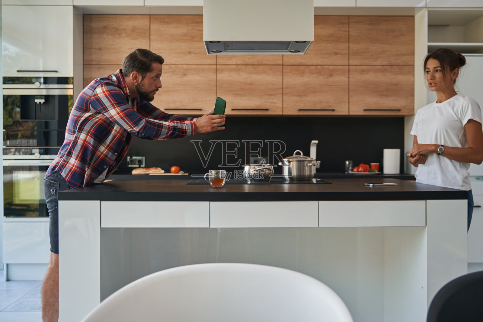 在现代家庭公寓里，英俊的男子向迷人的女士展示他的手机屏幕照片摄影图片