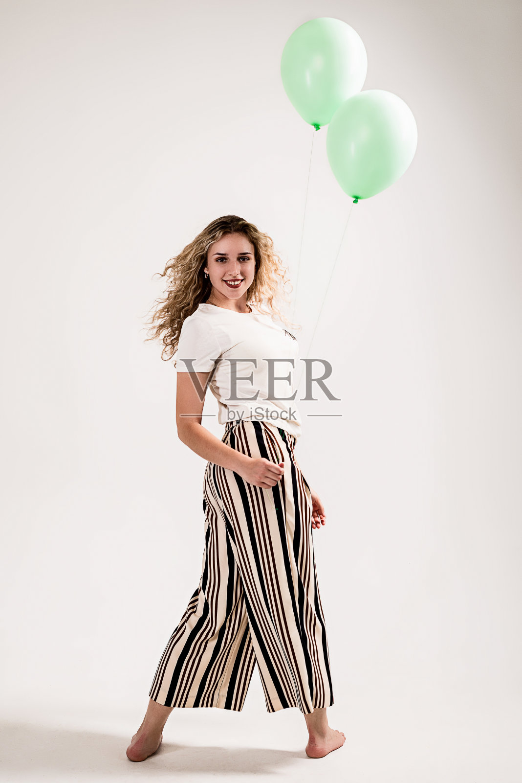 白色背景上有气球的卷发女孩照片摄影图片