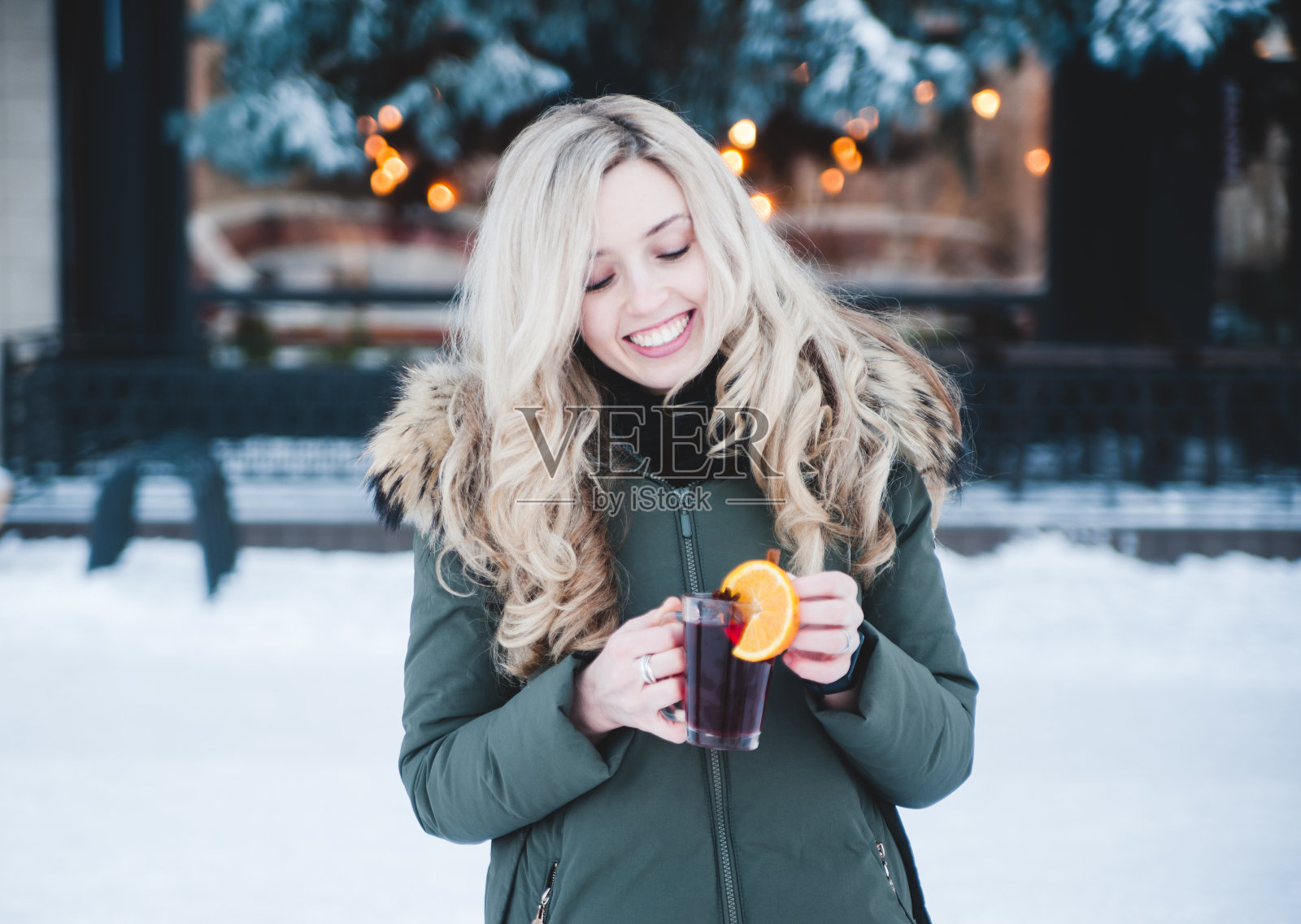 美丽微笑的女人在户外喝着热红酒。照片摄影图片