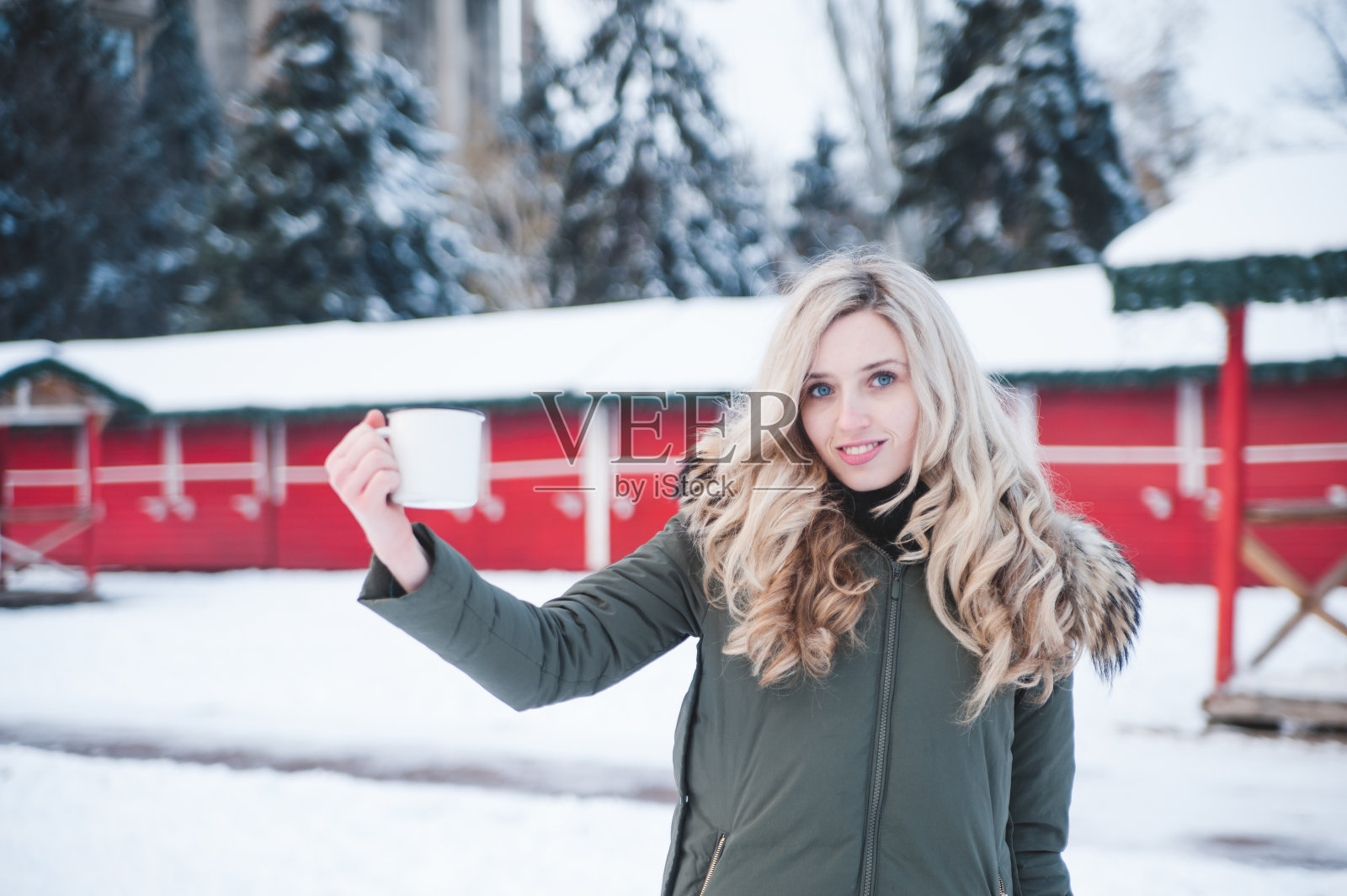 美丽的女人与一杯热饮在户外摆姿势。冬天的假期。照片摄影图片