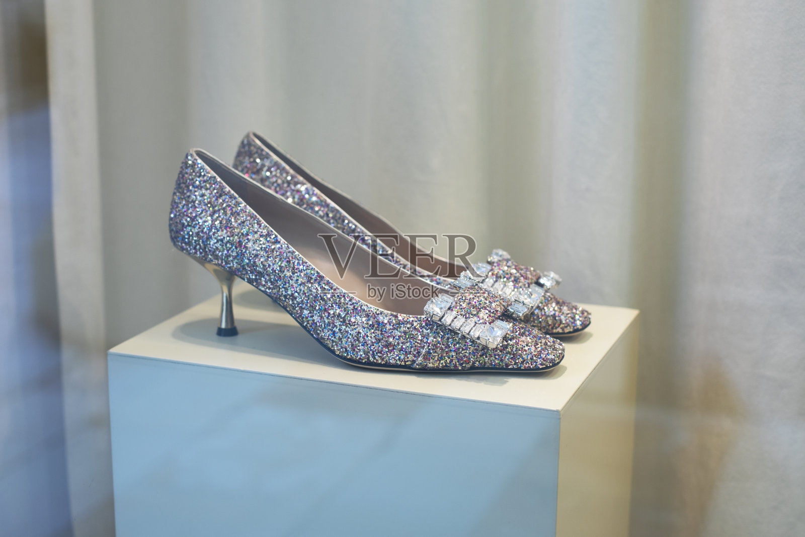 底座上闪闪发光的鞋子，镶着莱茵石的漂亮鞋子照片摄影图片