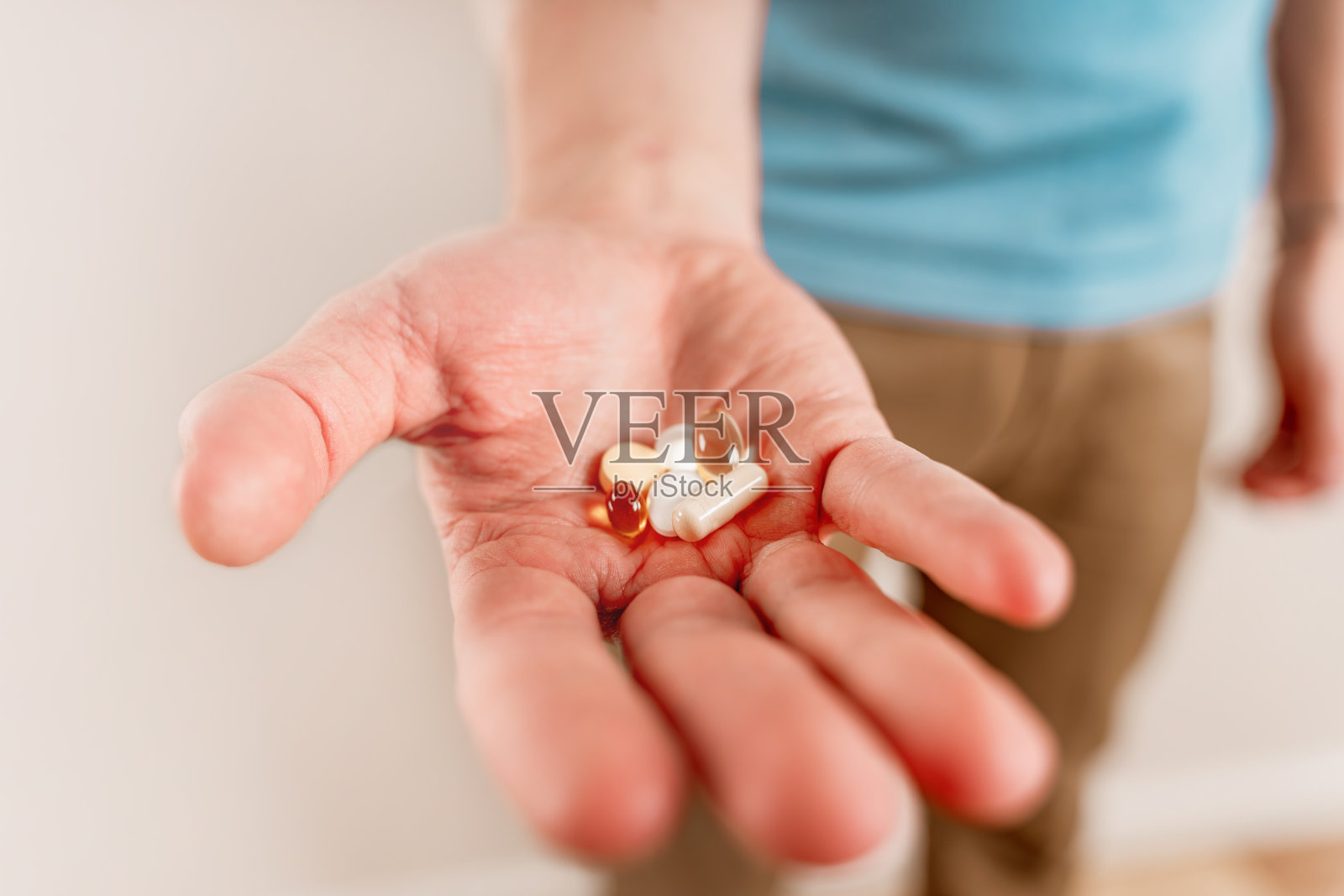 这个男人手里拿着药片和胶囊。吃维生素和药物，关门照片摄影图片